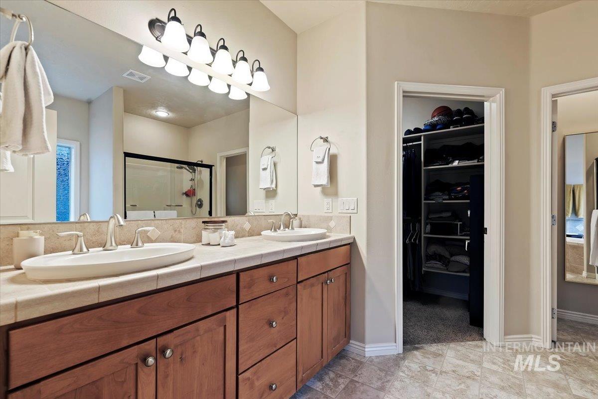 Bathroom with a shower stall, a walk in closet, and double vanity