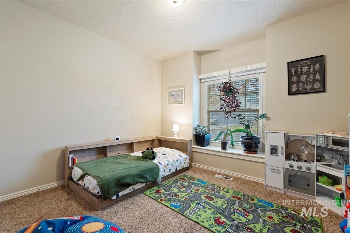 Carpeted bedroom with a textured ceiling and baseboards