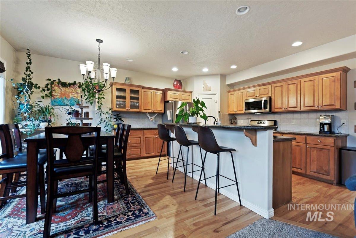Kitchen with a breakfast bar, glass insert cabinets, an island with sink, stainless steel appliances, and decorative backsplash