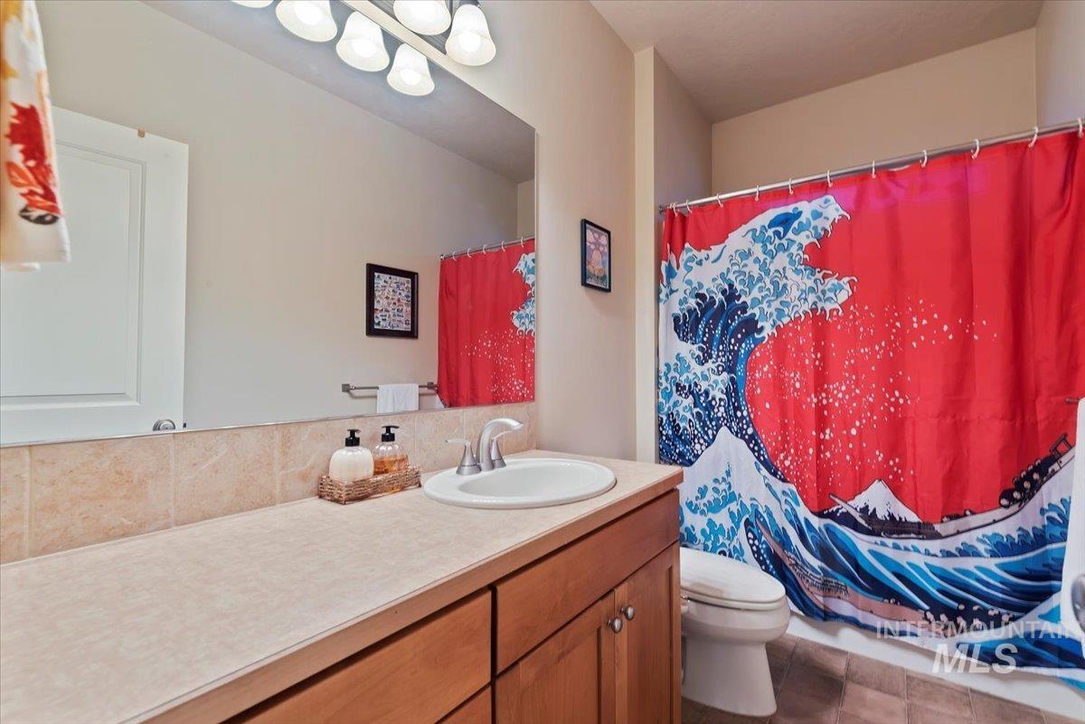 Bathroom with curtained shower, vanity, and tasteful backsplash