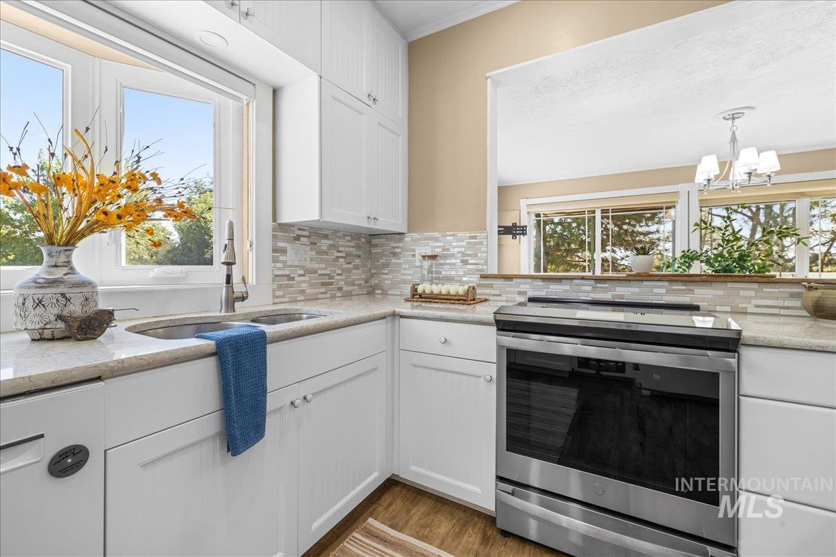 Kitchen featuring stainless steel induction stove, plenty of natural light, white cabinets, and light quartz counters