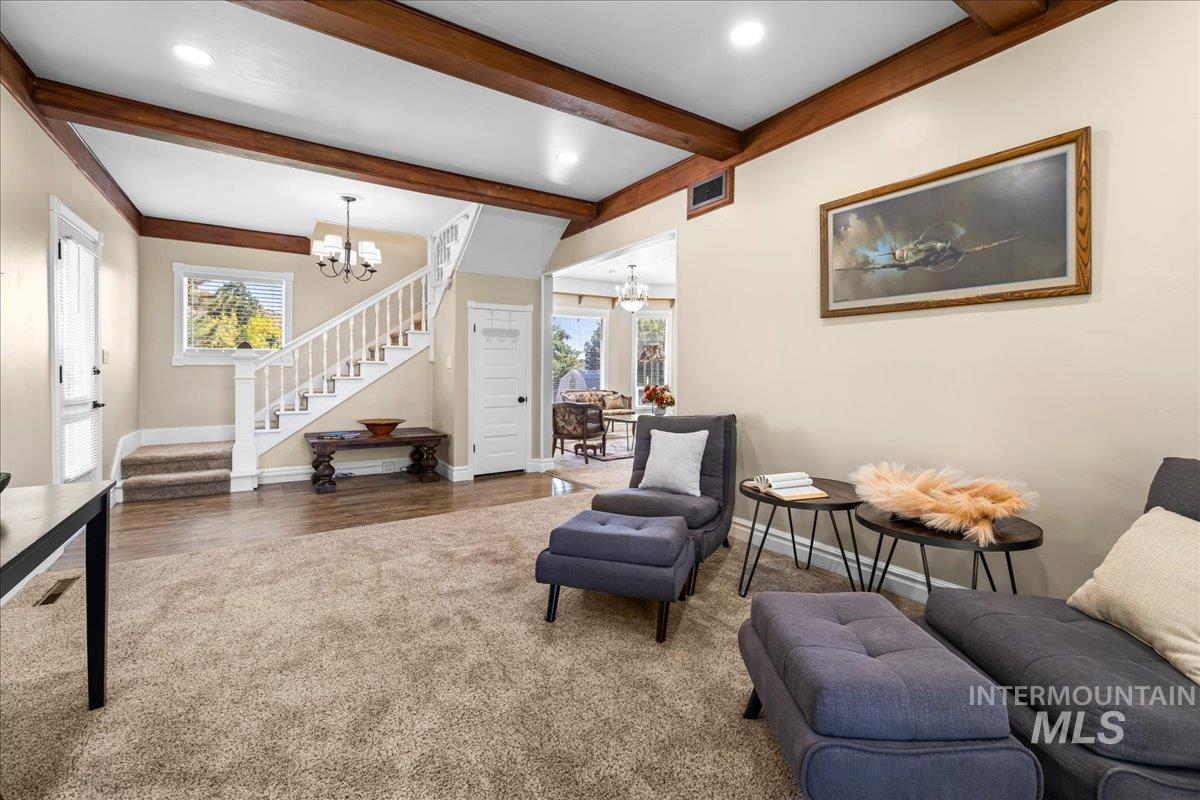 Living area with a chandelier, stairway, beam ceiling, dark wood-style finished floors, and recessed lighting