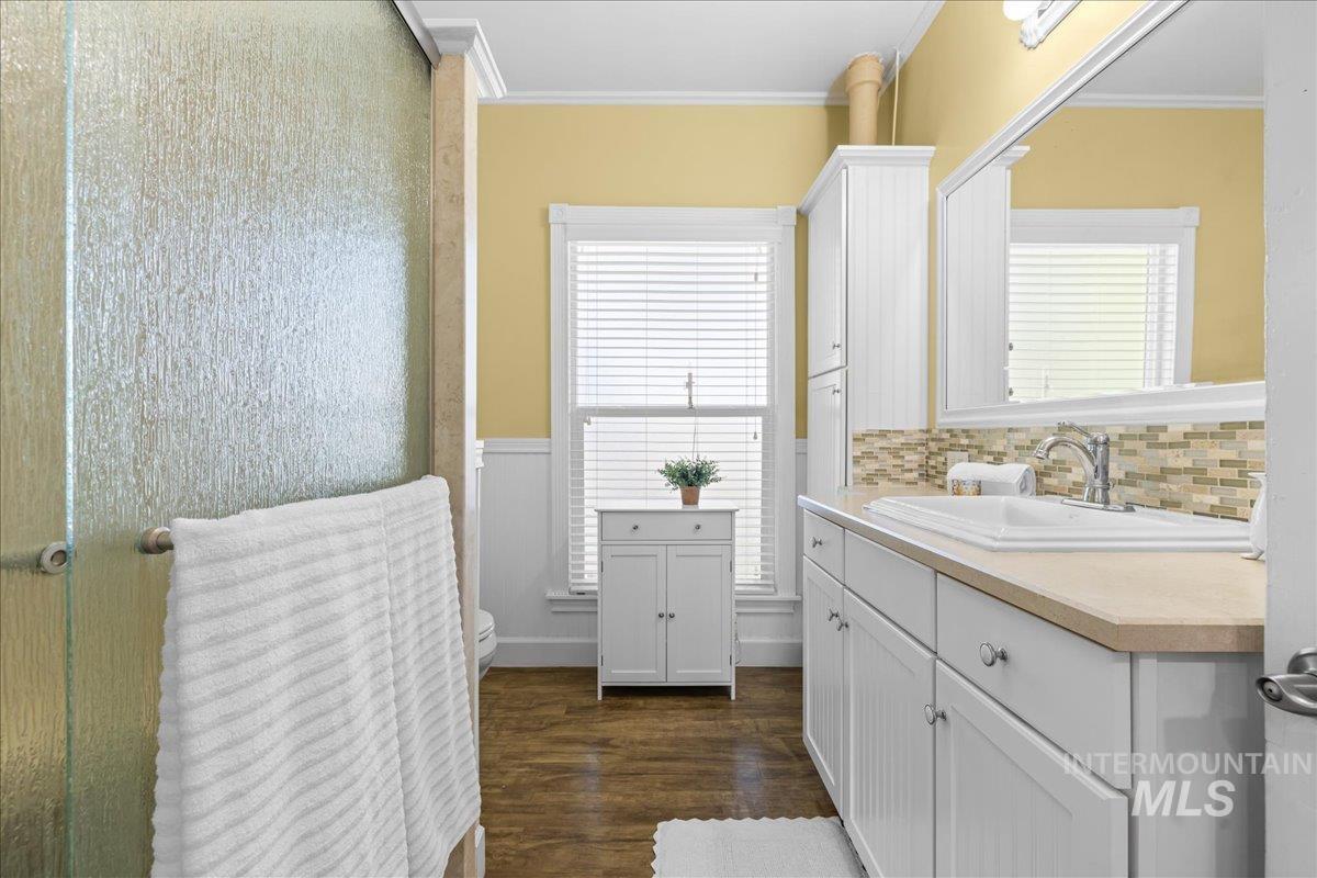 Full bathroom with vanity, dark wood-style flooring, and ornamental molding