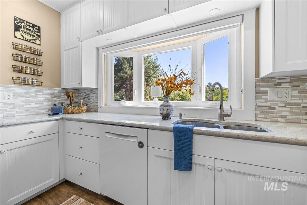 Kitchen with tasteful backsplash, white cabinetry, and light quartz counters.