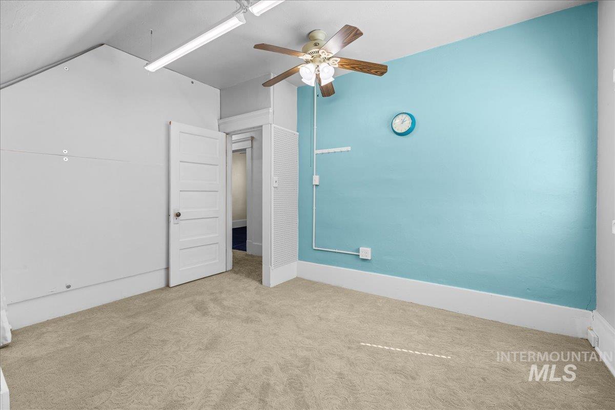 Unfurnished bedroom featuring carpet flooring, a ceiling fan, and lofted ceiling