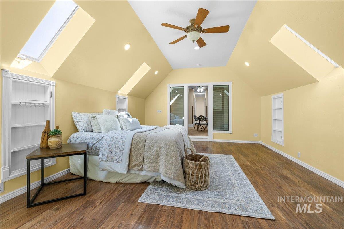 Bedroom with a skylight, dark wood-type flooring, a ceiling fan, lofted ceiling, and recessed lighting