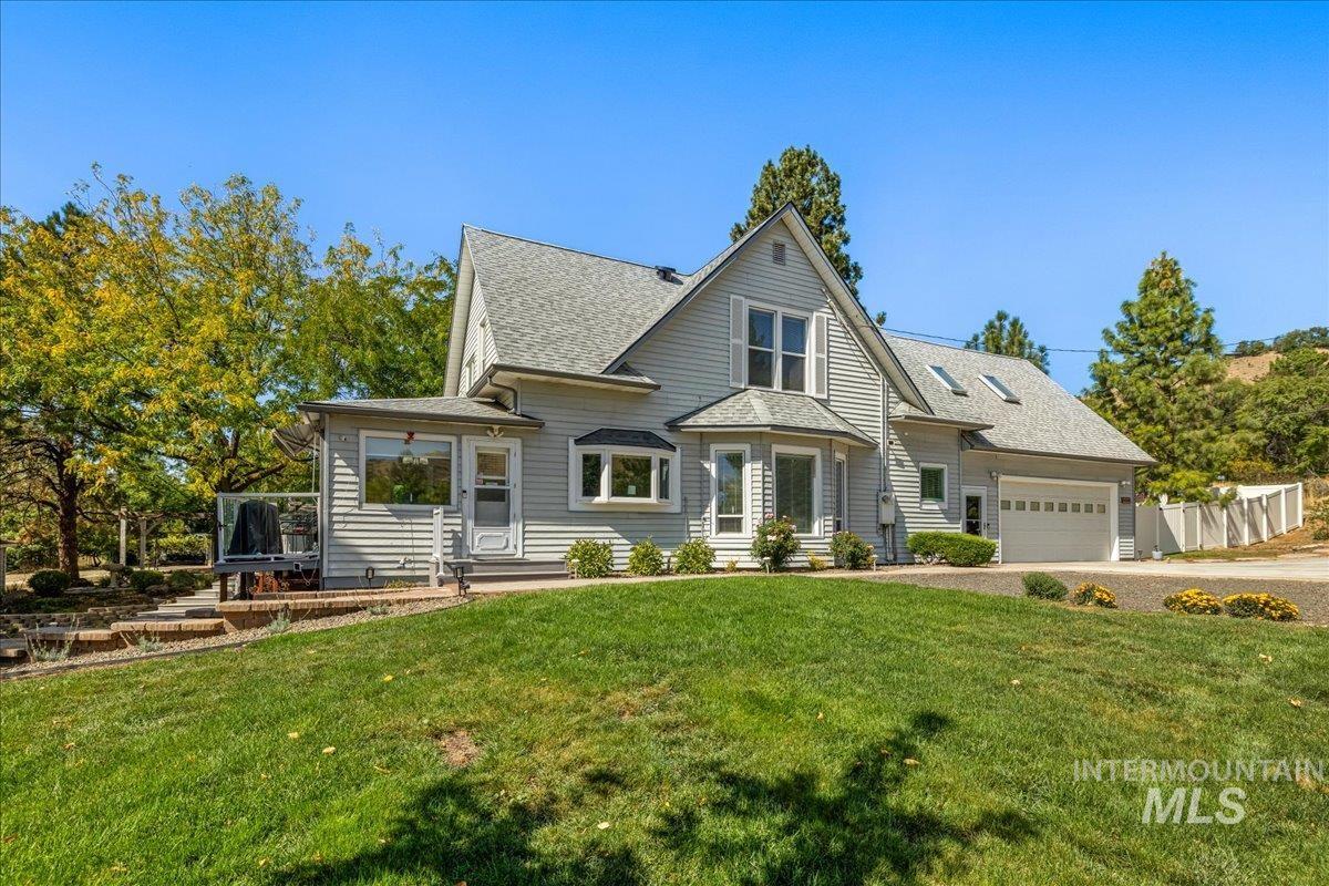 View of front of home with a shingled roof, driveway, a front yard, and a garage