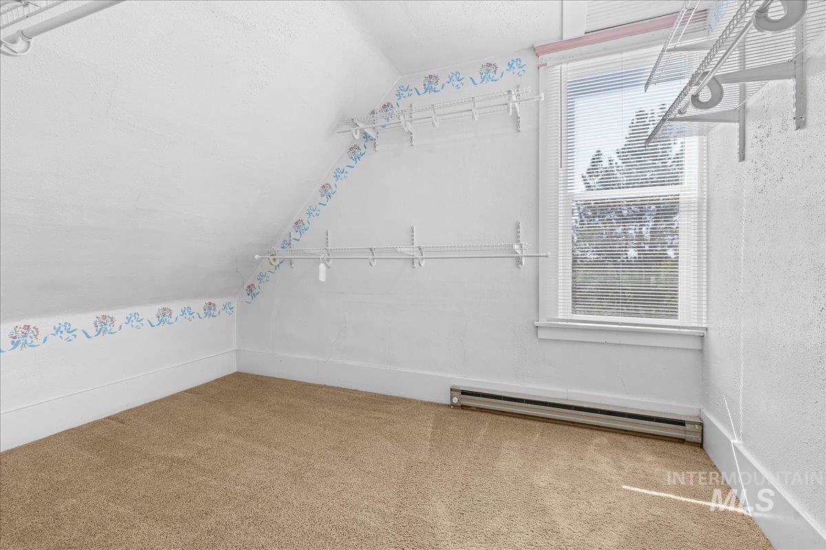 Featuring lofted ceiling, carpet floors, and a baseboard heating unit