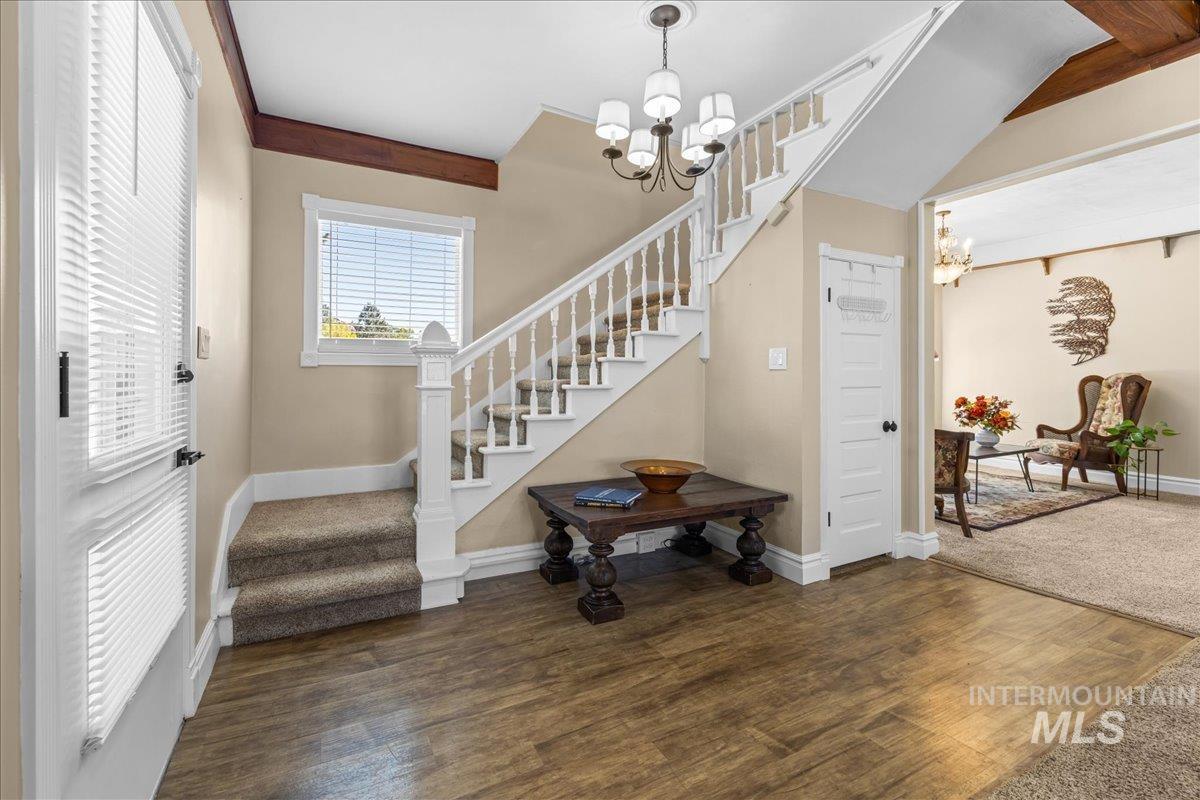 Entrance foyer featuring a chandelier, stairway, and dark wood-style flooring