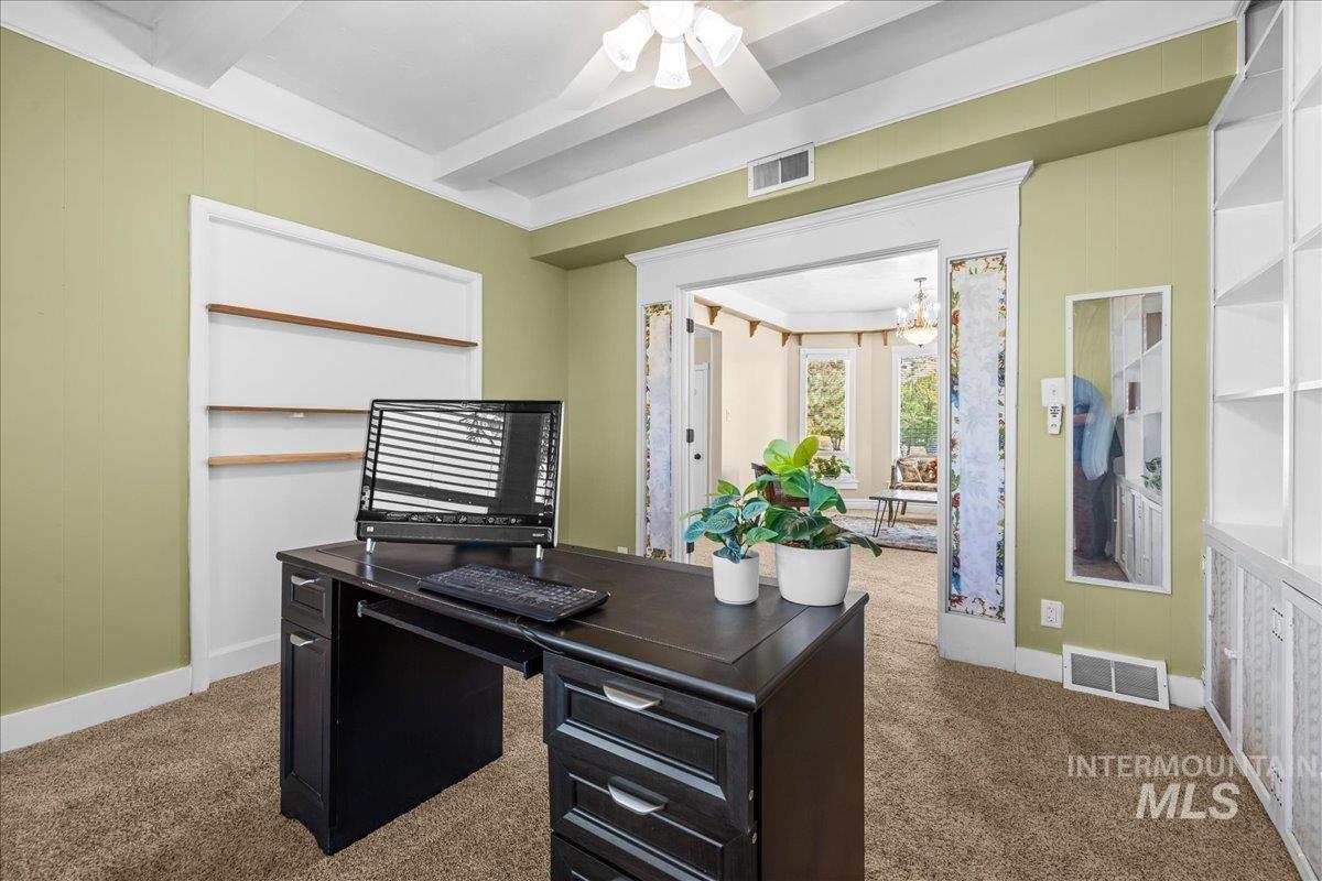 Office with dark carpet and beamed ceiling