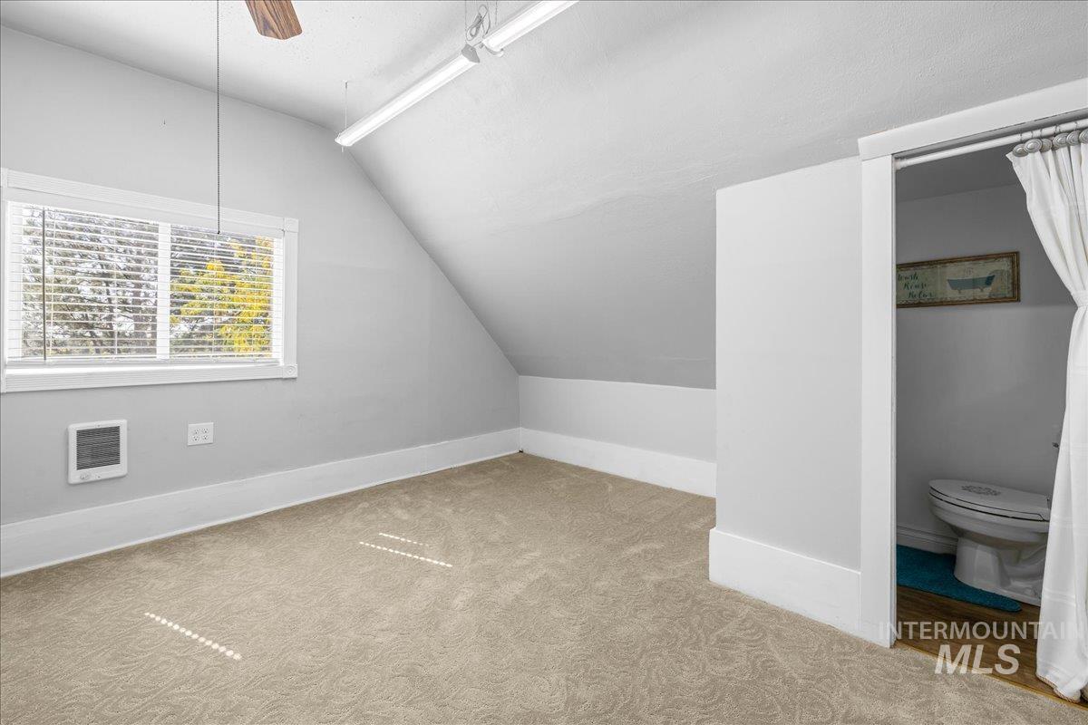 Featuring vaulted ceiling, light carpet, and ceiling fan