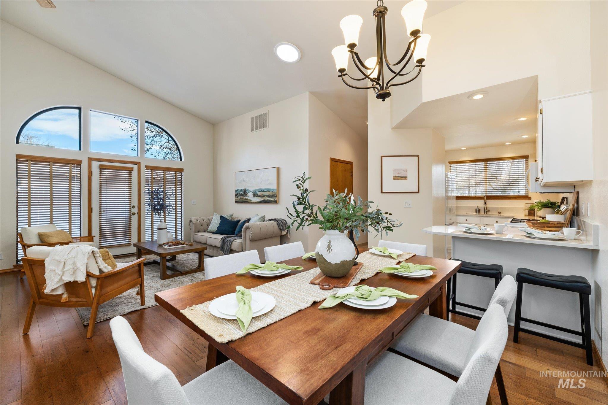 Dining area with wood-type flooring, a chandelier, and lofted ceiling