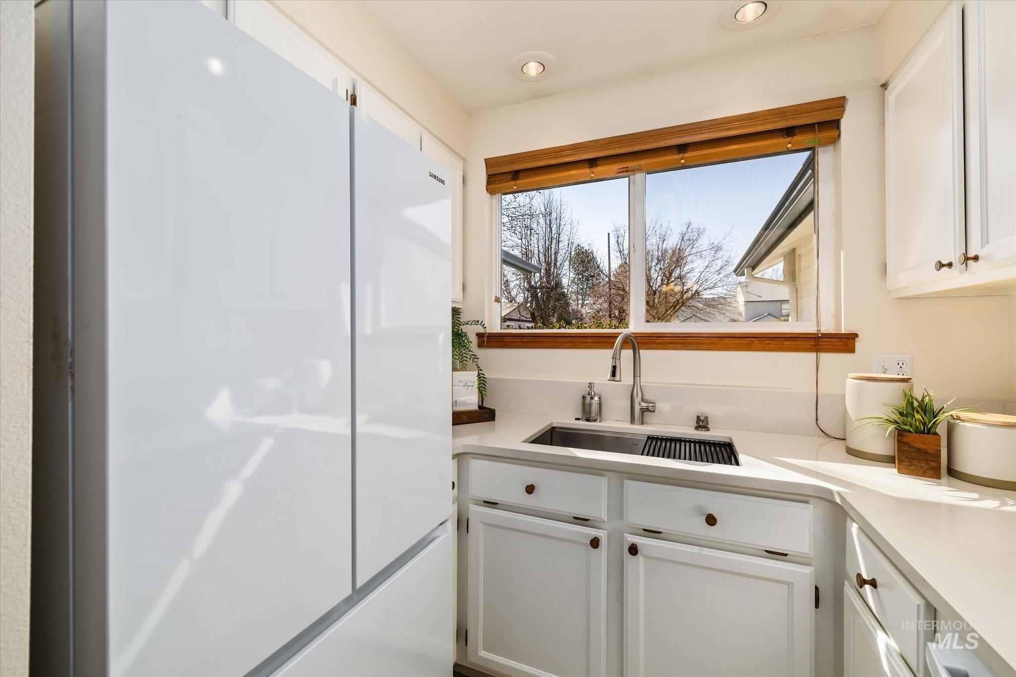 Kitchen with freestanding refrigerator, white cabinetry, and recessed lighting