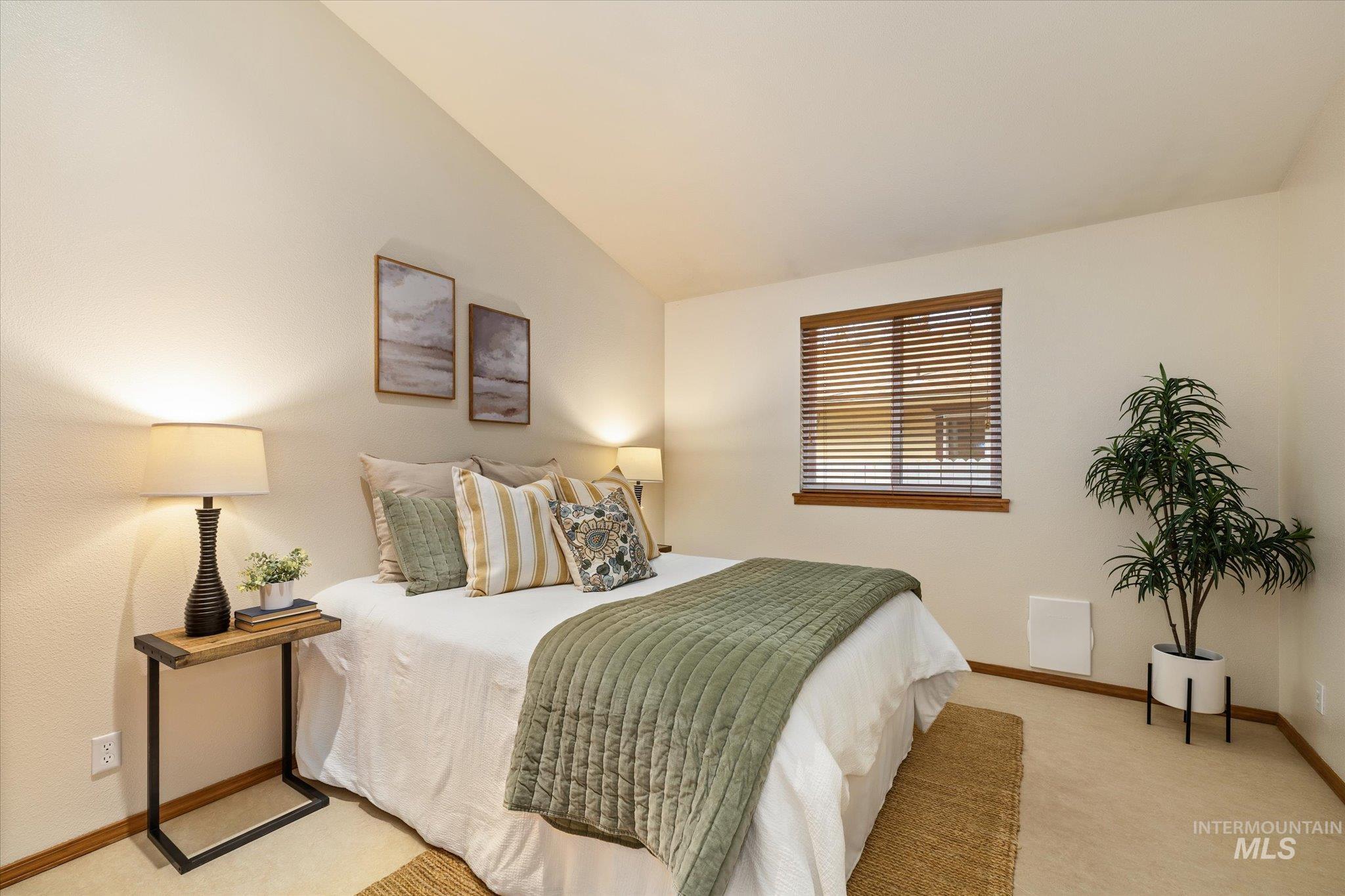 Bedroom with lofted ceiling and light carpet