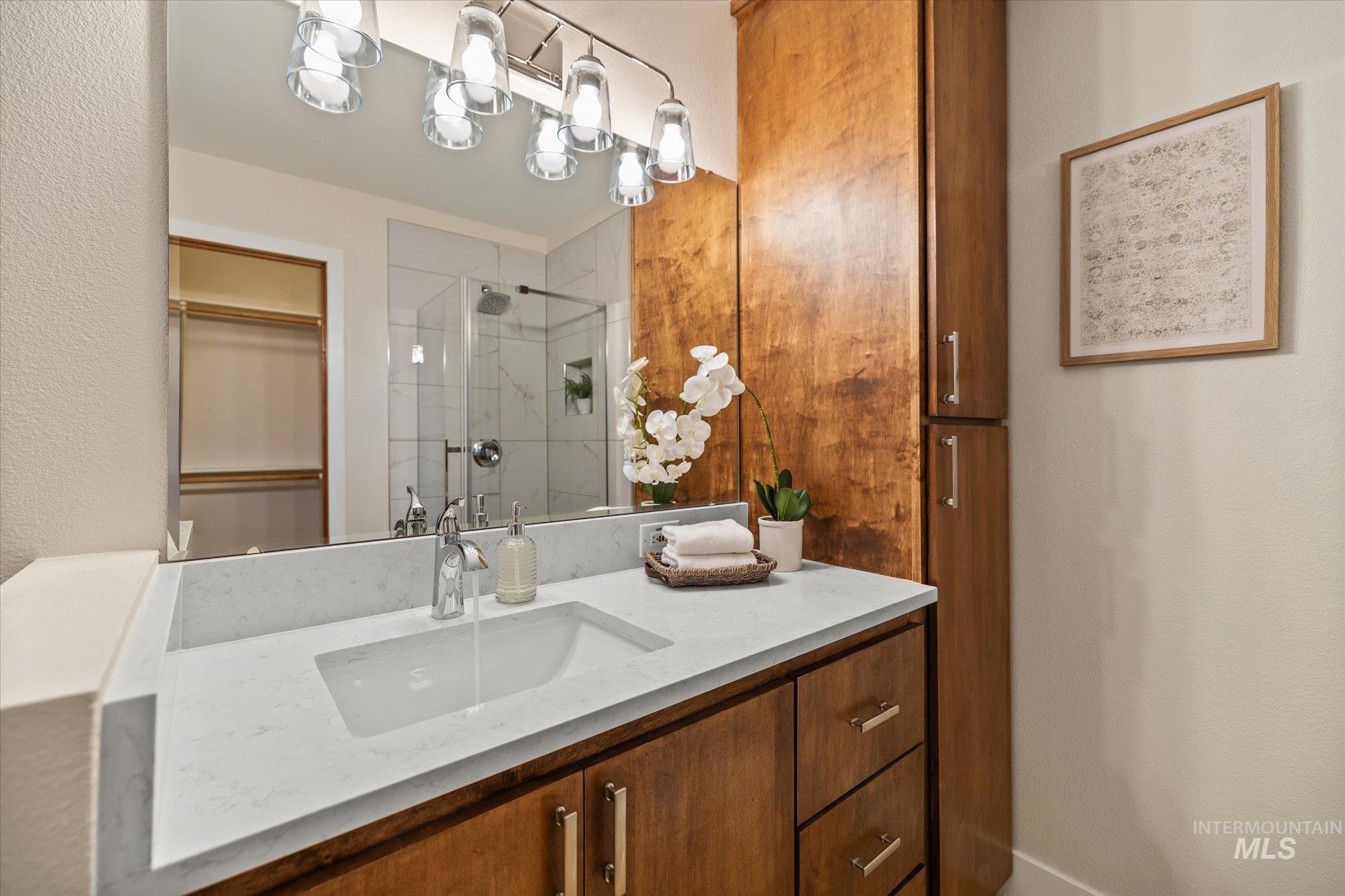 Full bath featuring a marble finish shower, vanity, and a spacious closet