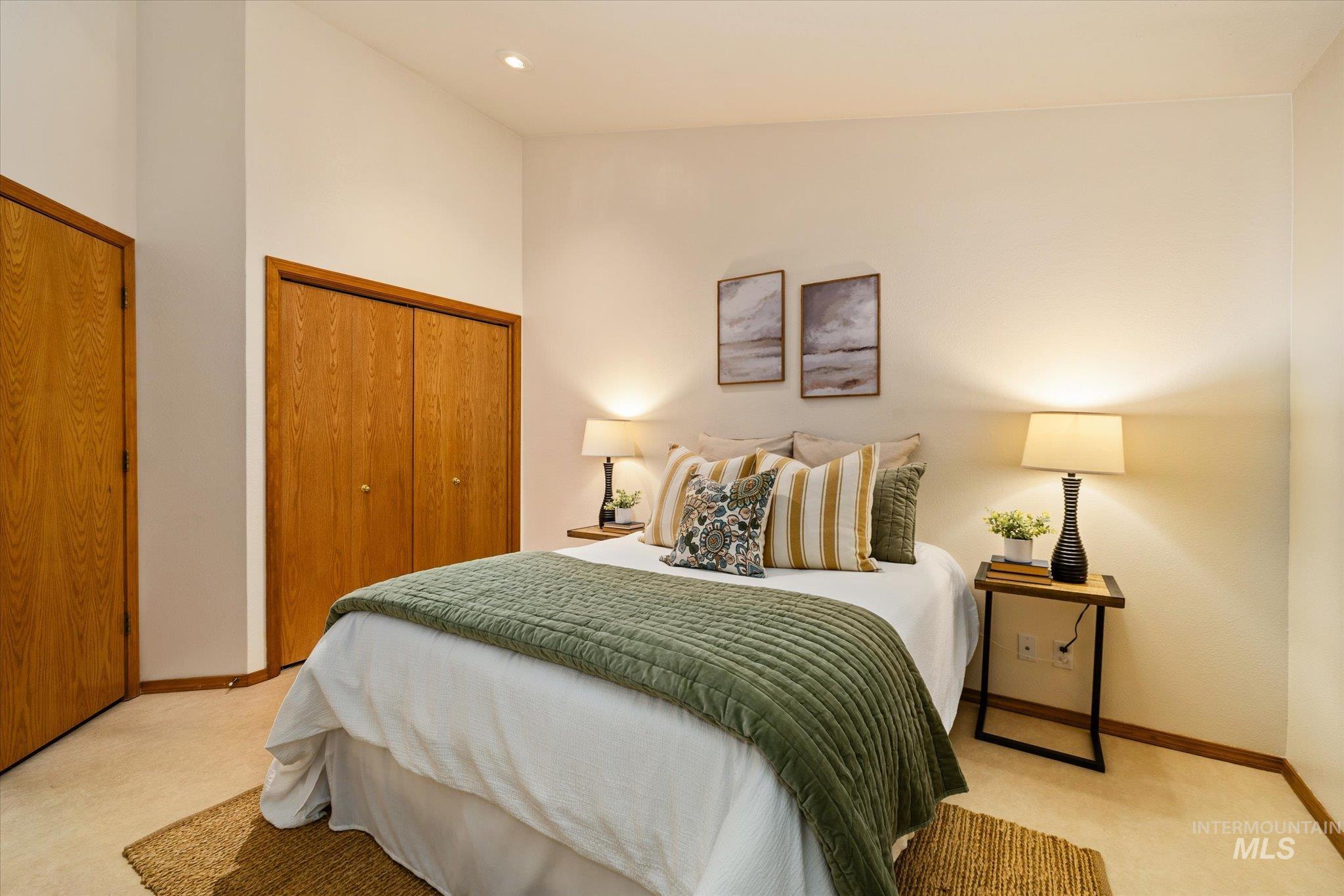 Bedroom featuring multiple closets, light colored carpet, recessed lighting, and a high ceiling