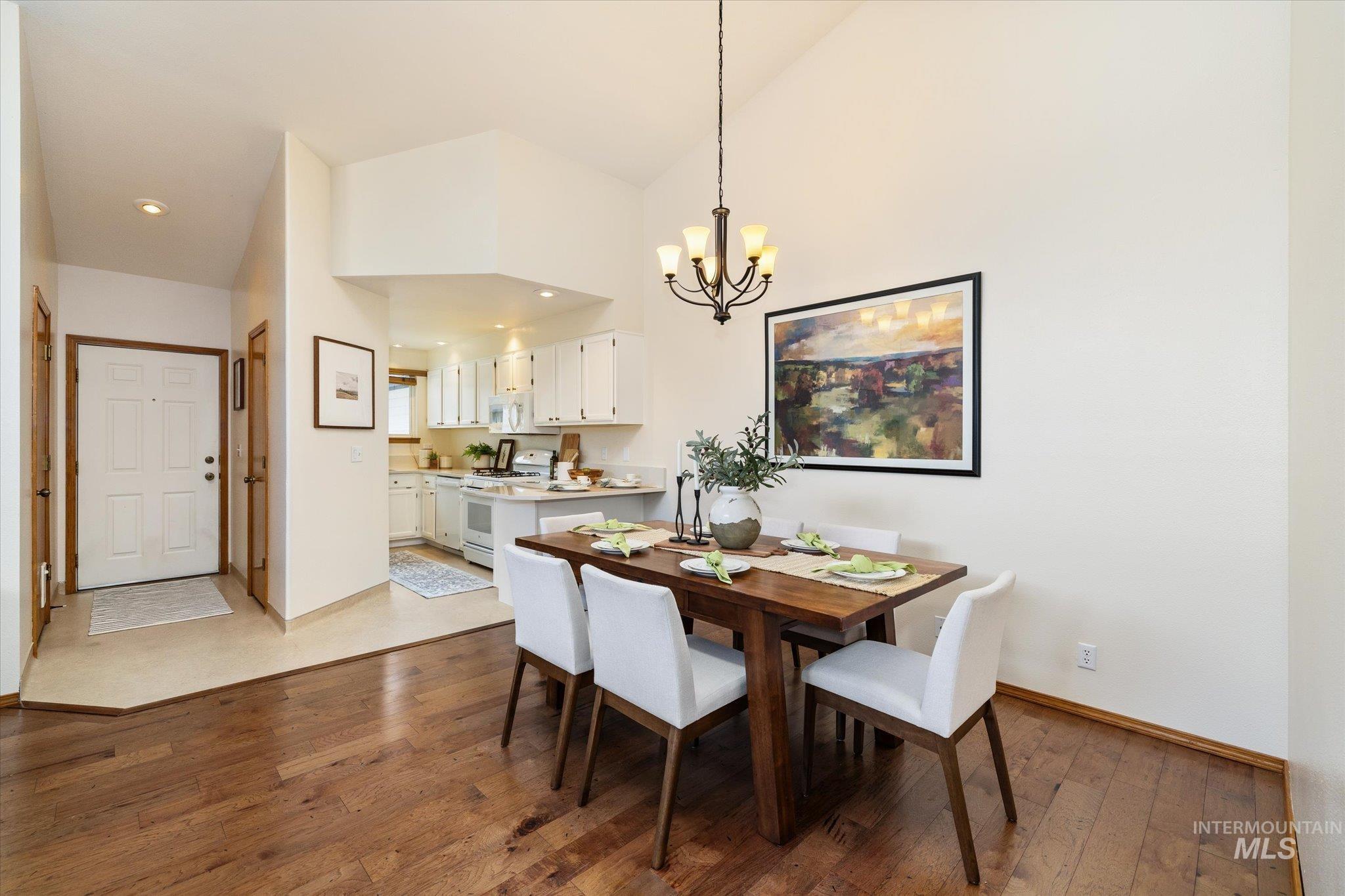Dining room featuring dark wood-style floors, suspended lighting, and lofted ceiling