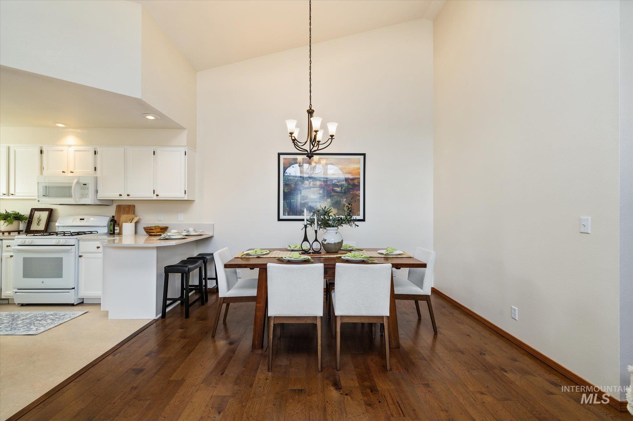 Dining area with a chandelier, dark wood-type flooring, and lofted ceiling