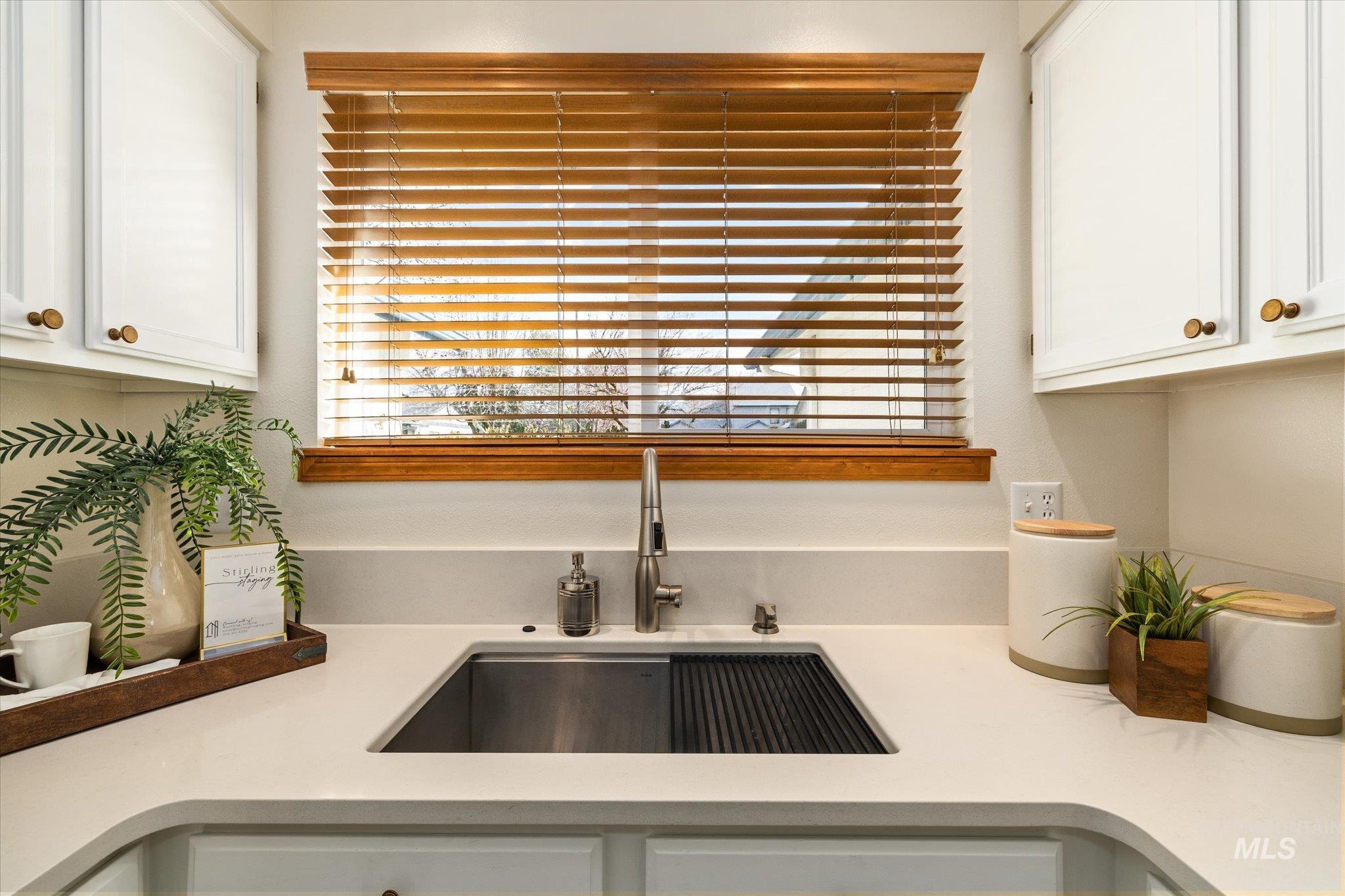 Kitchen view of white cabinetry and light stone counters