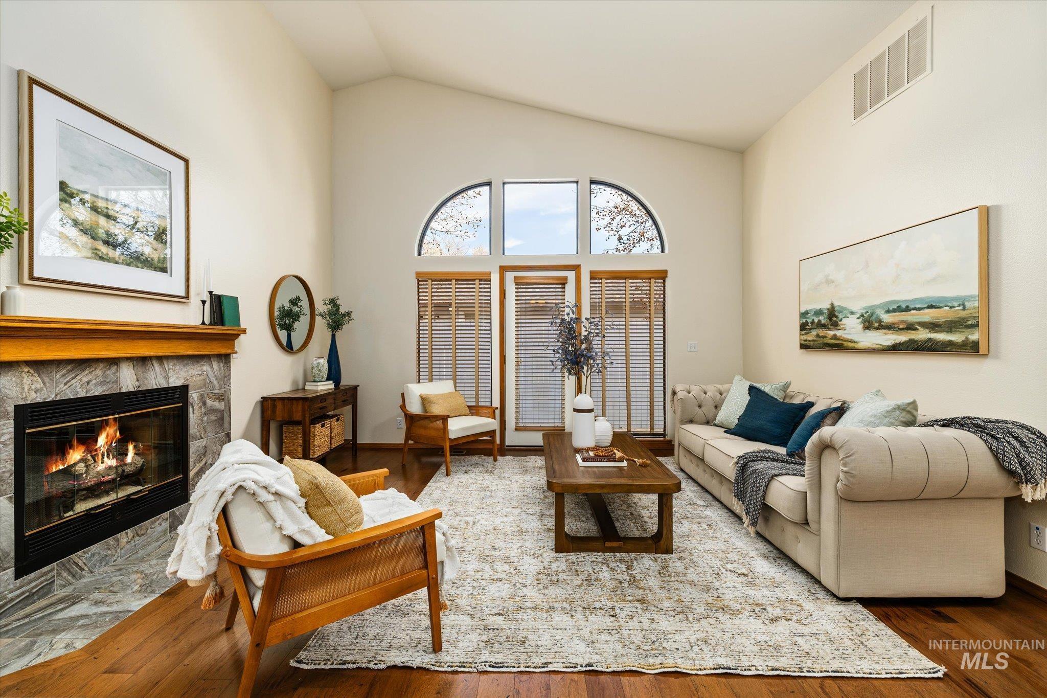 Living room with vaulted ceiling, a fireplace with flush hearth, and wood-type flooring