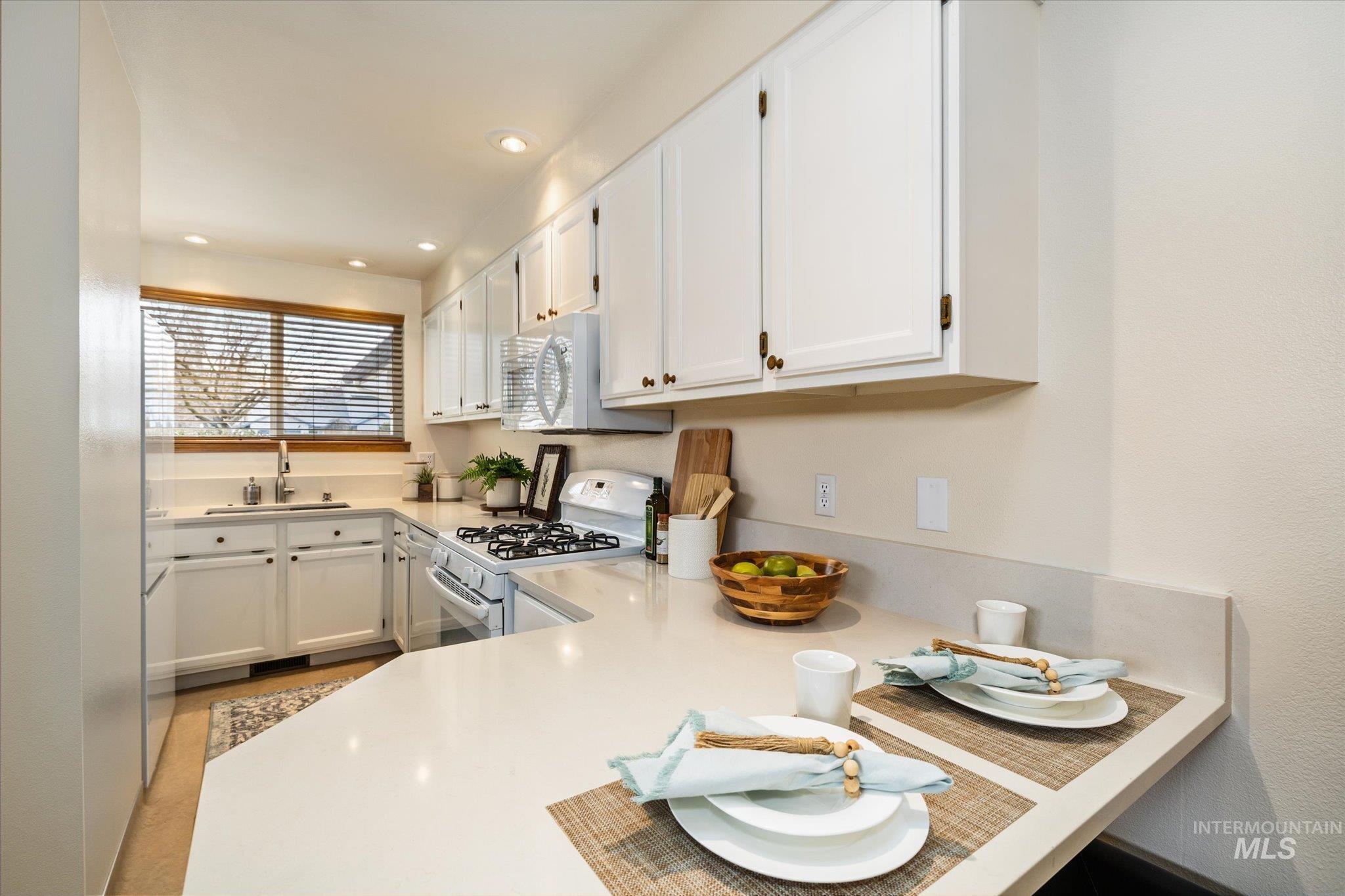 Kitchen with white cabinetry, white appliances, and recessed lighting