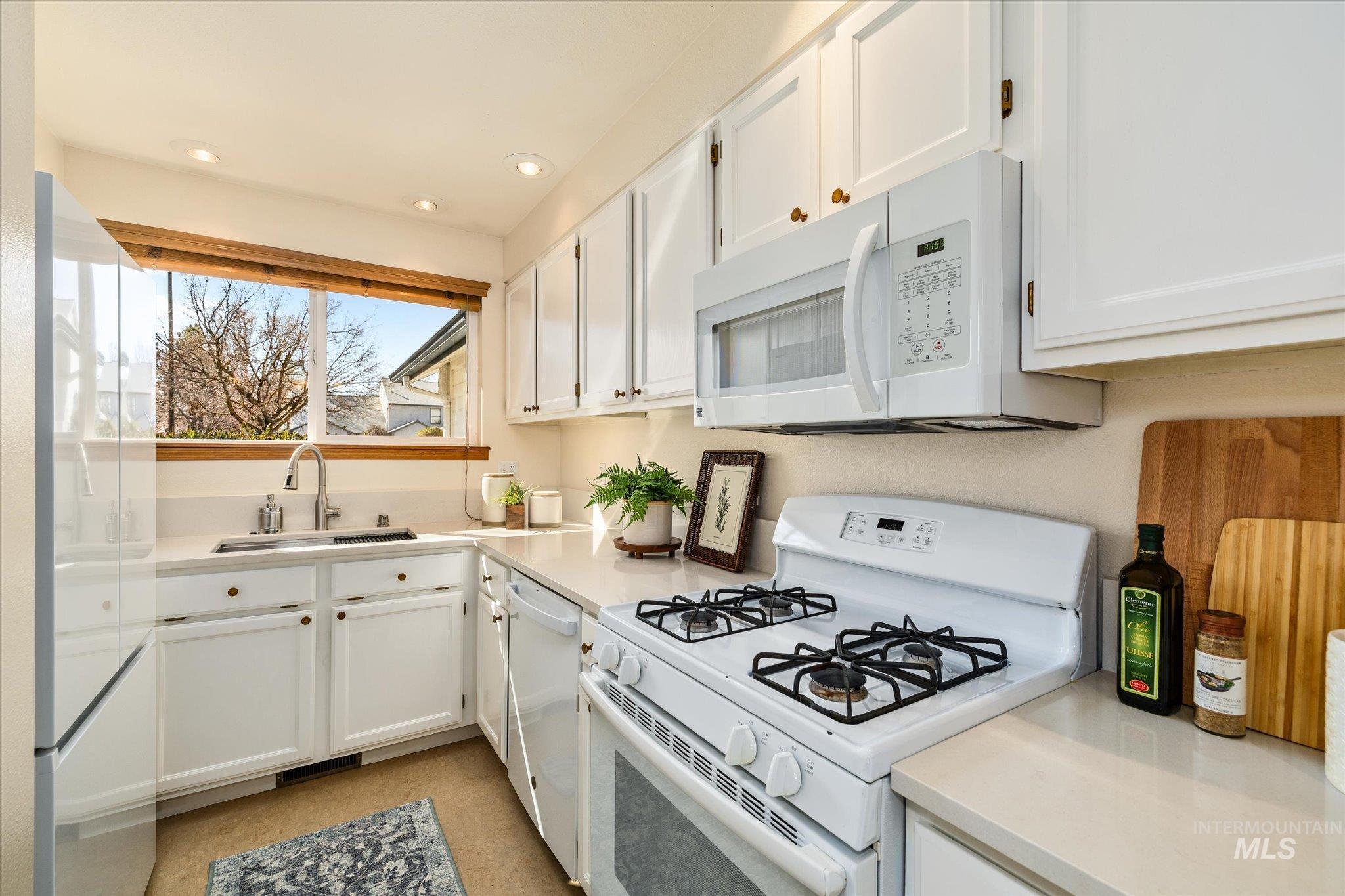 Kitchen featuring white appliances, white cabinetry, light countertops, and recessed lighting