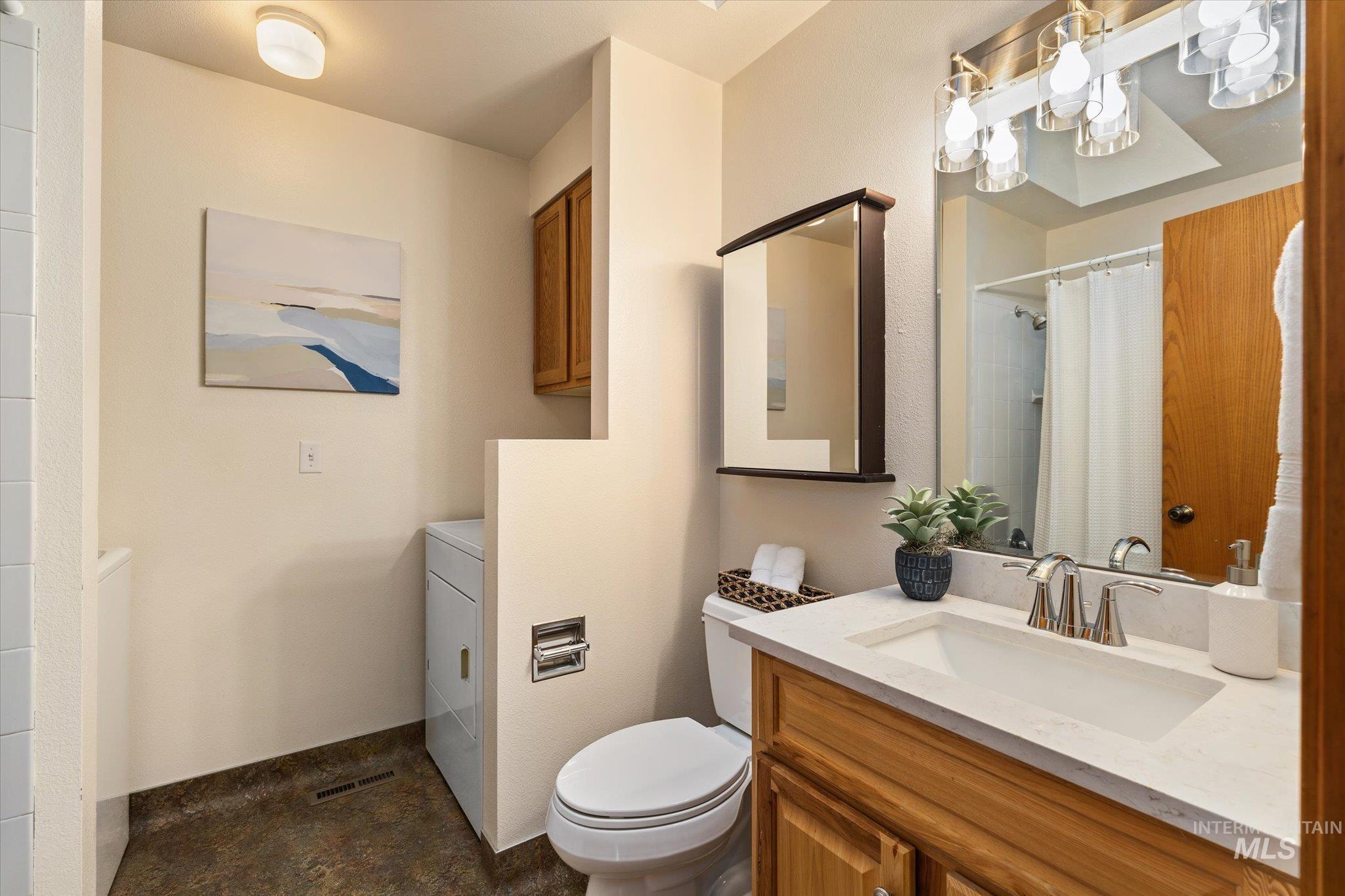Full bath featuring vanity, a shower with curtain, and washer / dryer