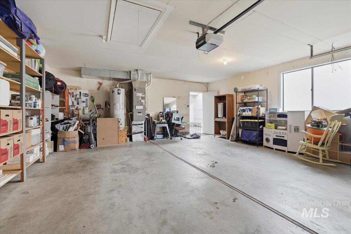 Garage with water heater, heating unit, and a garage door opener
