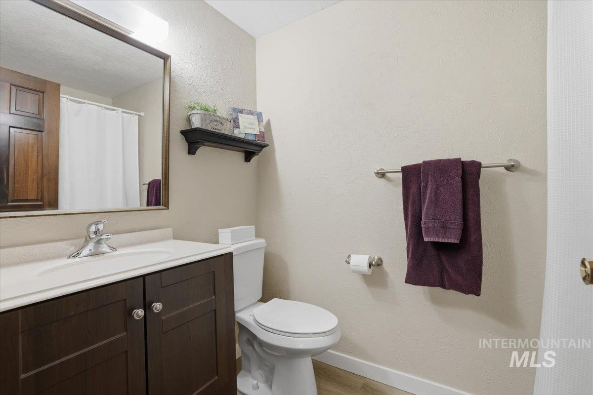 Bathroom with vanity, a shower with curtain, a textured wall, and light wood-type flooring