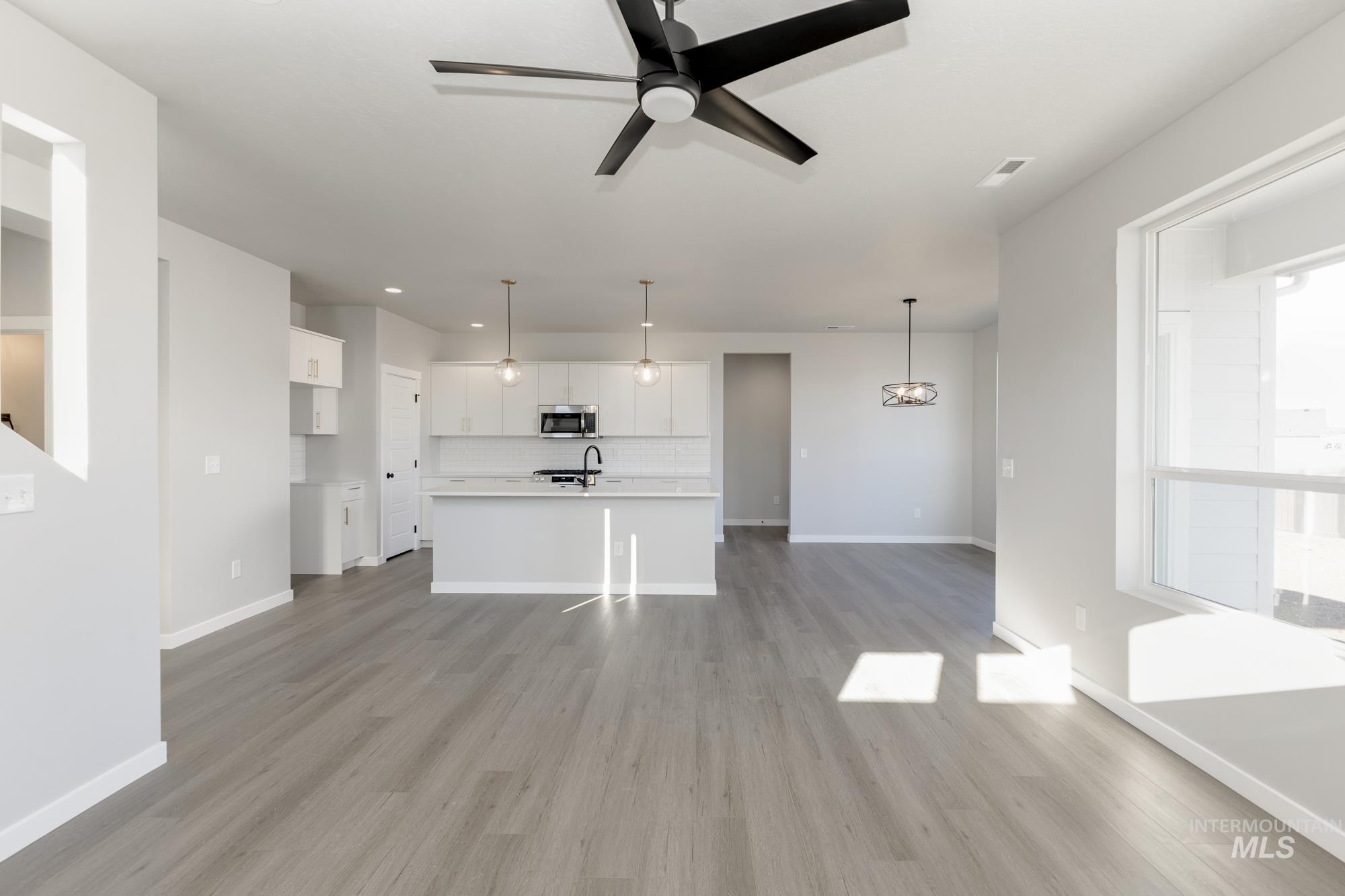 Unfurnished living room featuring a ceiling fan, light wood-style flooring, and recessed lighting