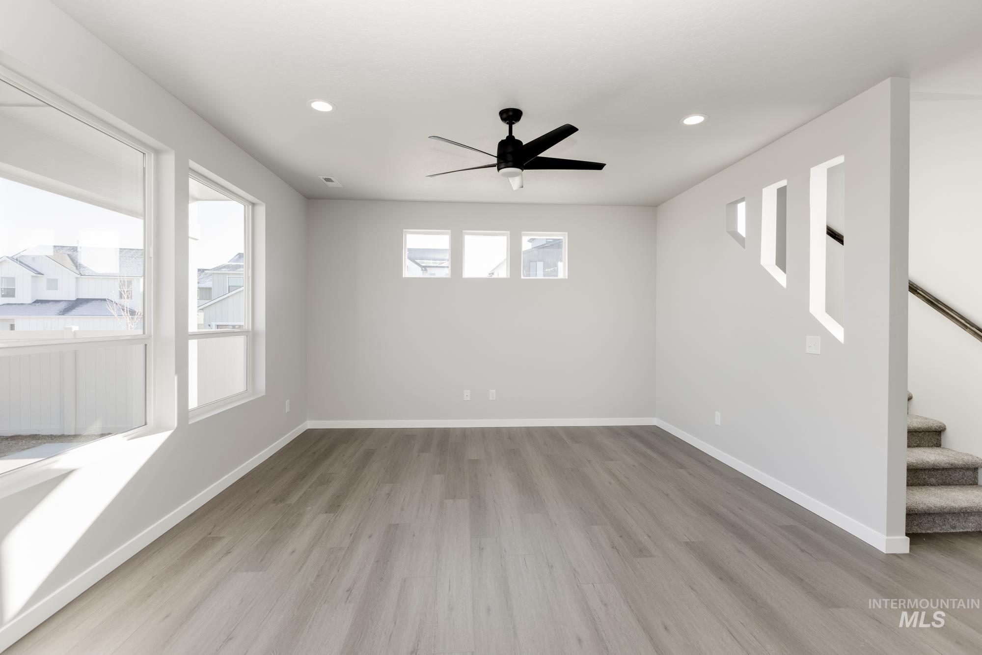 Spare room featuring light wood-type flooring, stairs, recessed lighting, and ceiling fan