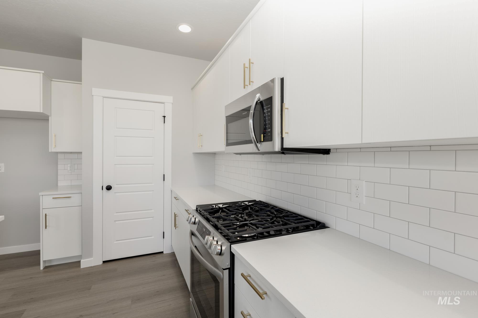Kitchen featuring stainless steel appliances, white cabinetry, decorative backsplash, dark wood finished floors, and recessed lighting