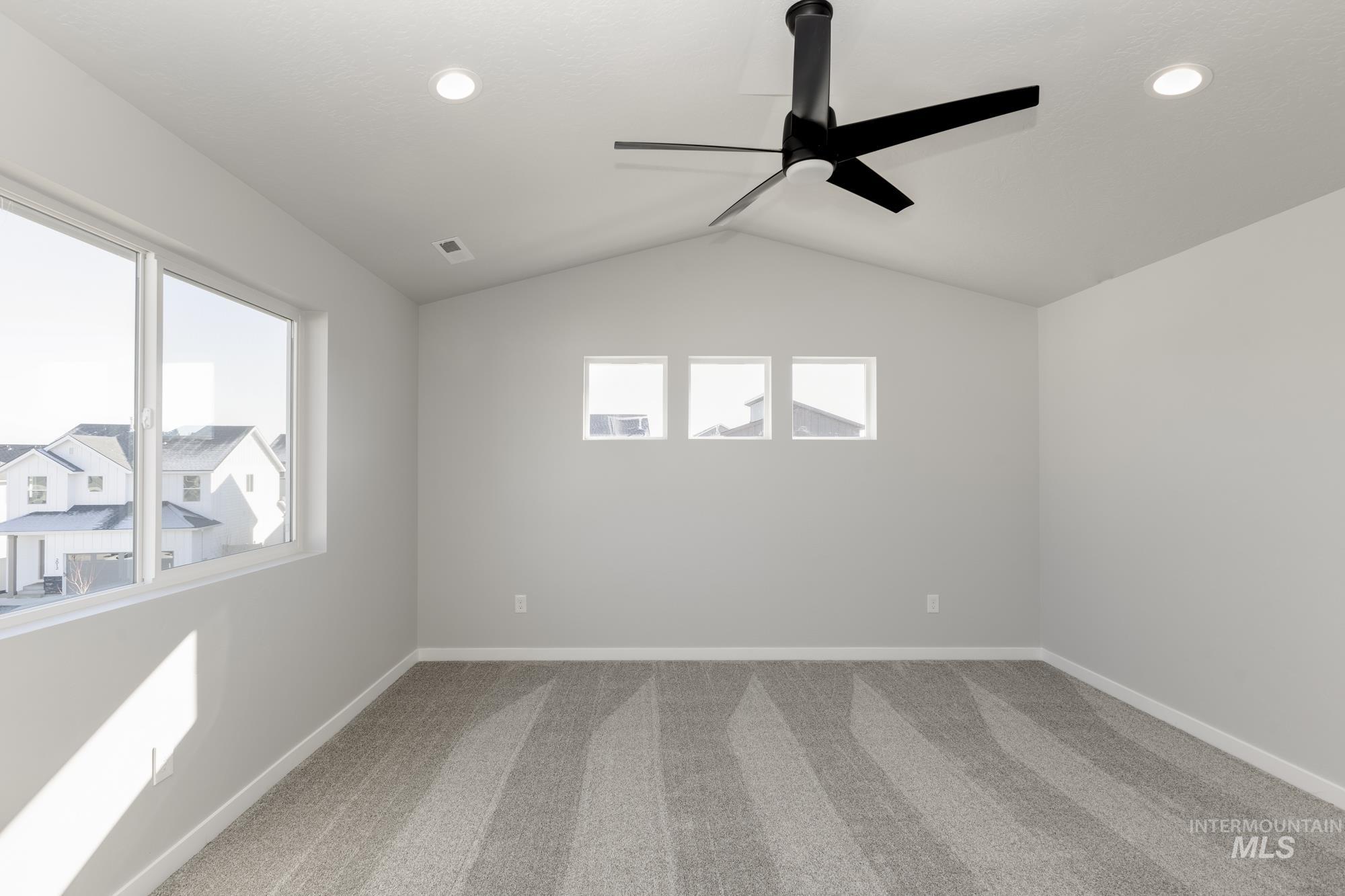 Empty room featuring carpet flooring, lofted ceiling, and ceiling fan