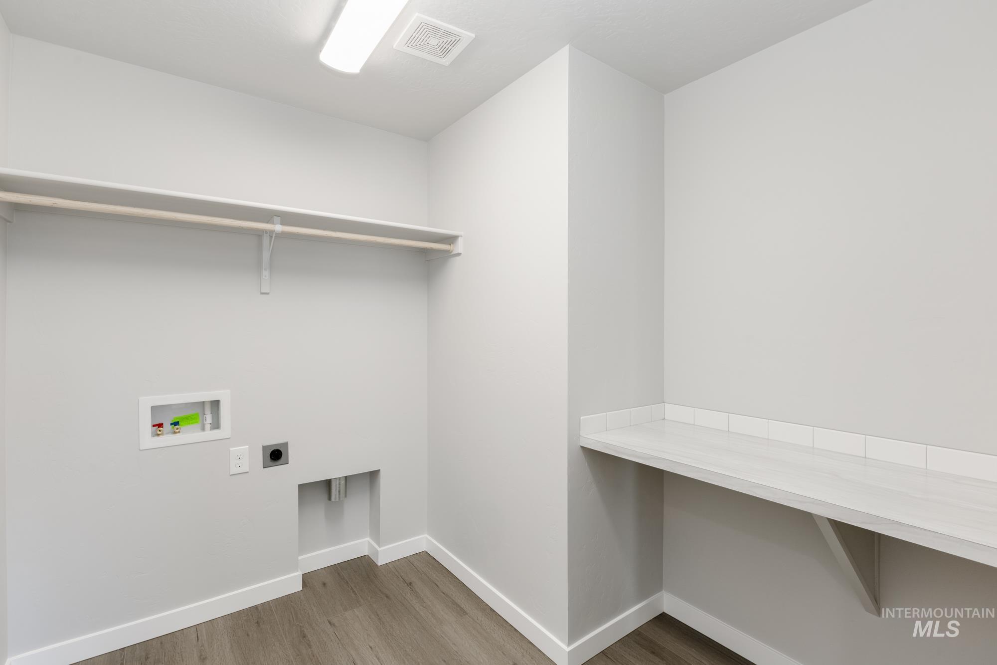 Washroom with light wood finished floors, hookup for an electric dryer, and washer hookup