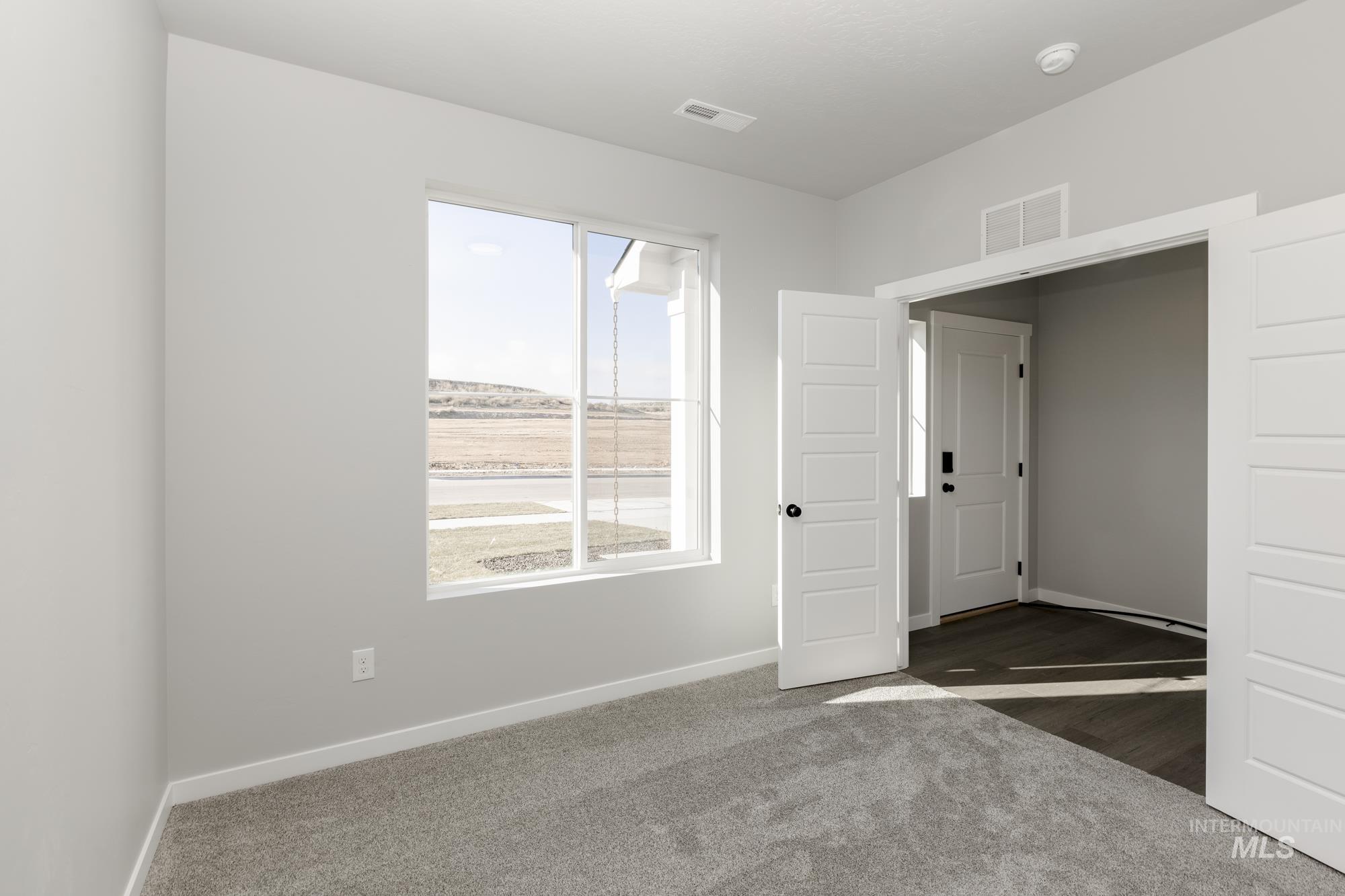 Empty room featuring dark colored carpet and baseboards