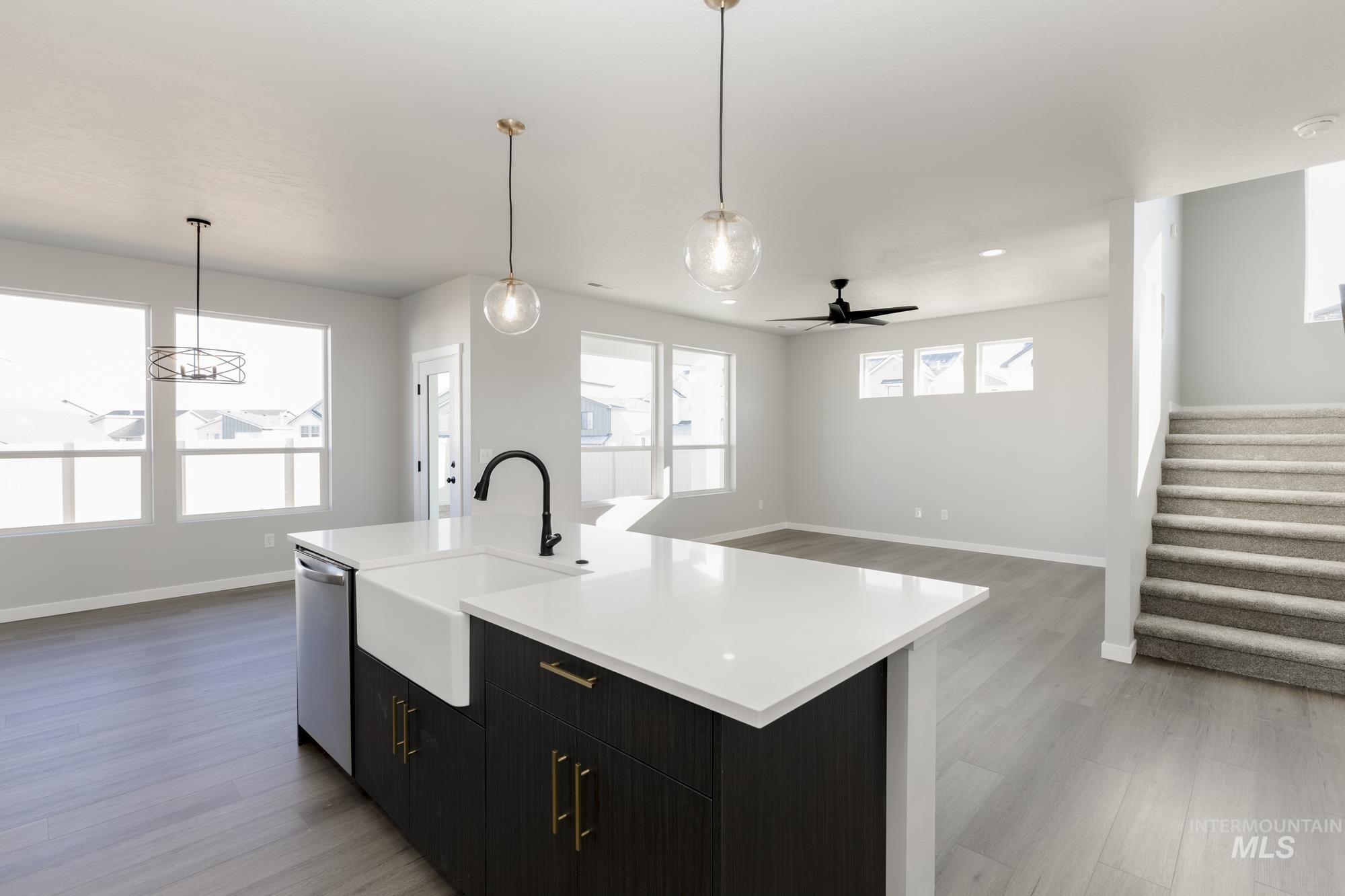 Kitchen with a ceiling fan, open floor plan, hanging light fixtures, and a kitchen island with sink