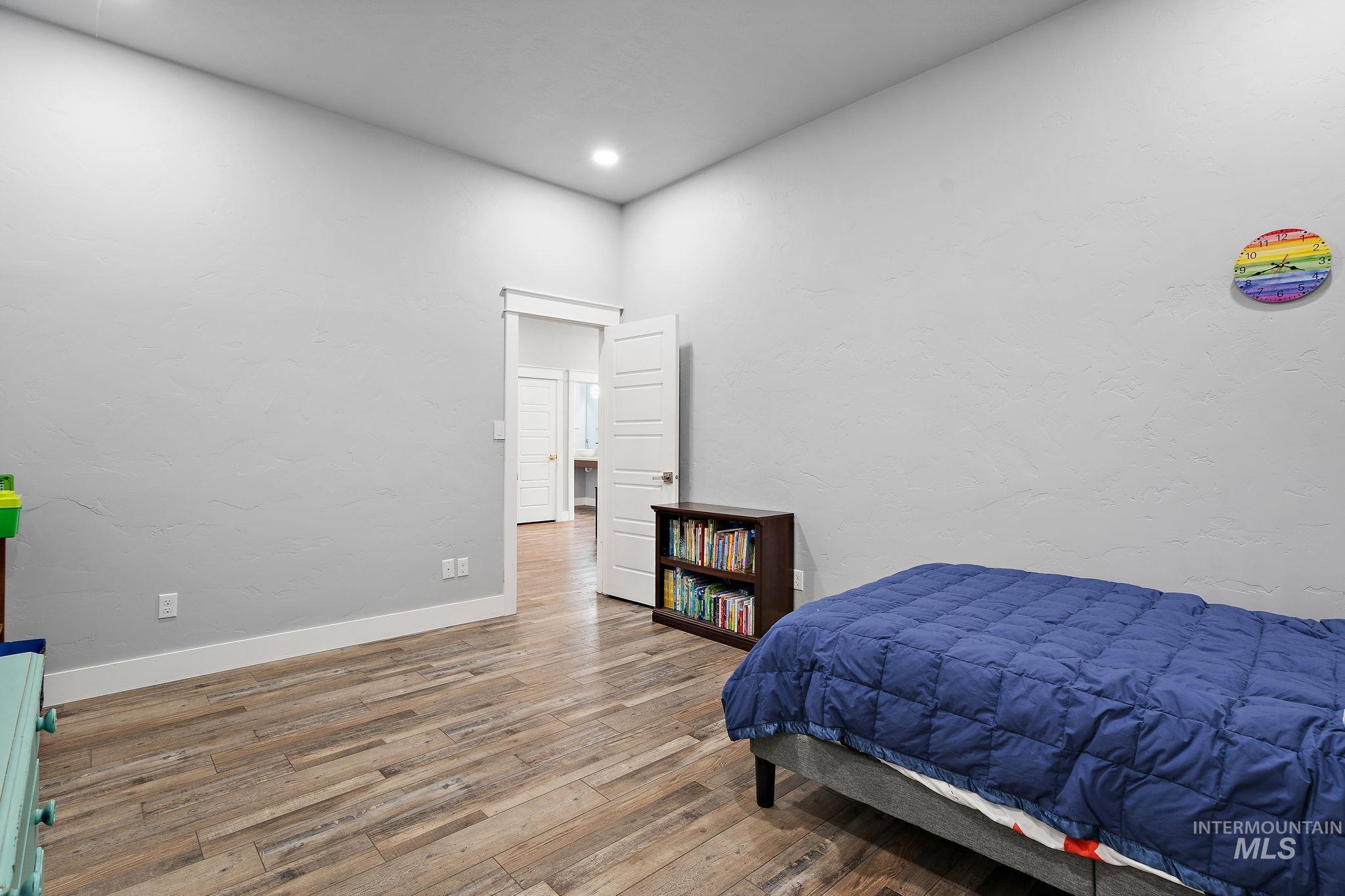 Bedroom with wood finished floors, a textured wall, and recessed lighting