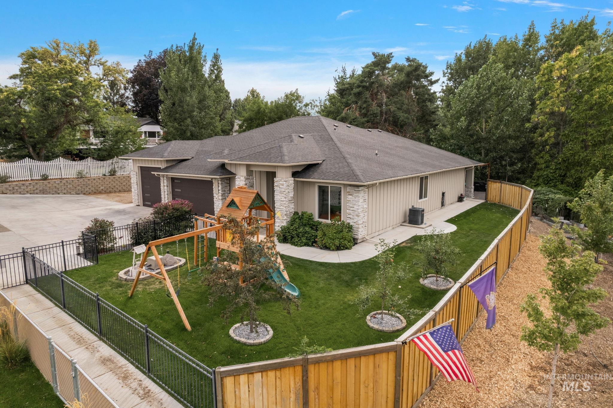 View of front of home featuring a garage, roof with shingles, a playground, driveway, and stone siding