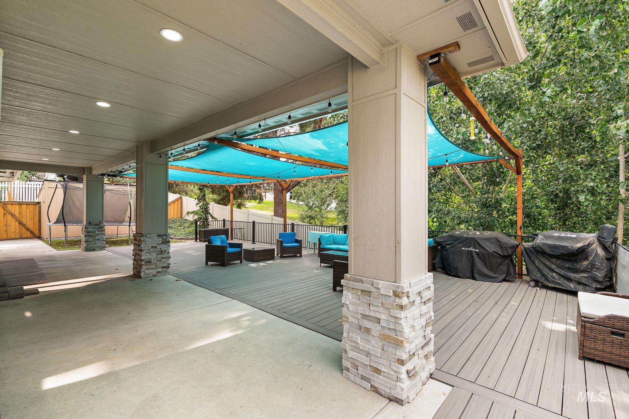 Fenced backyard featuring an outdoor living space, a patio, a grill, and a deck