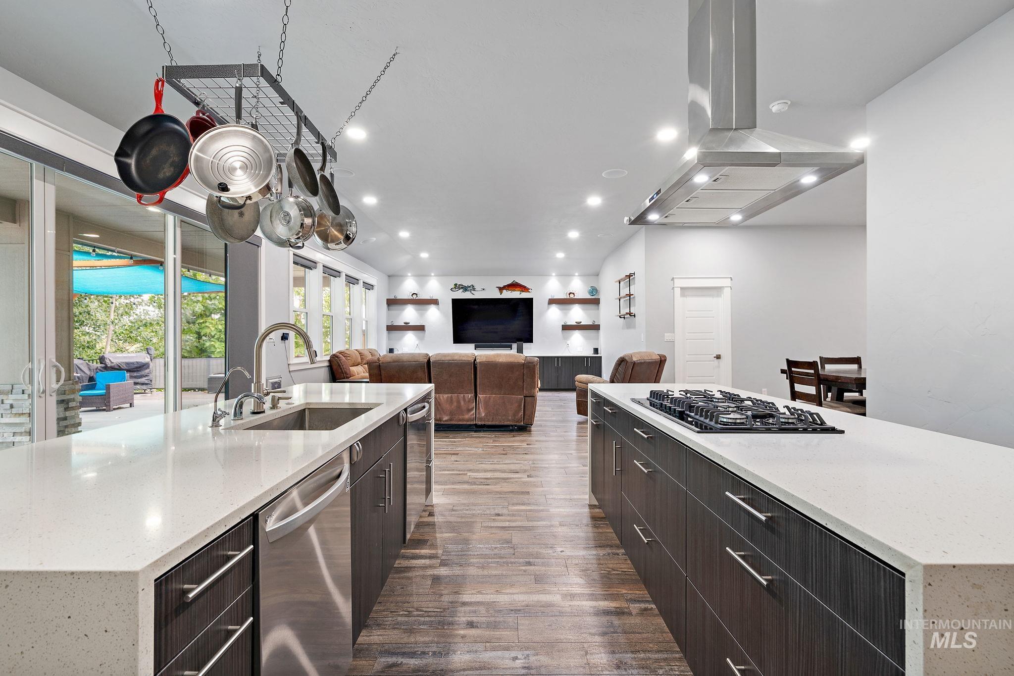 Kitchen with light stone countertops, a large island, wood-type flooring, dishwasher, and island exhaust hood