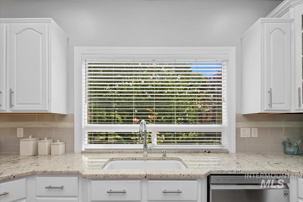 Kitchen featuring white cabinetry, tasteful backsplash, and dishwasher