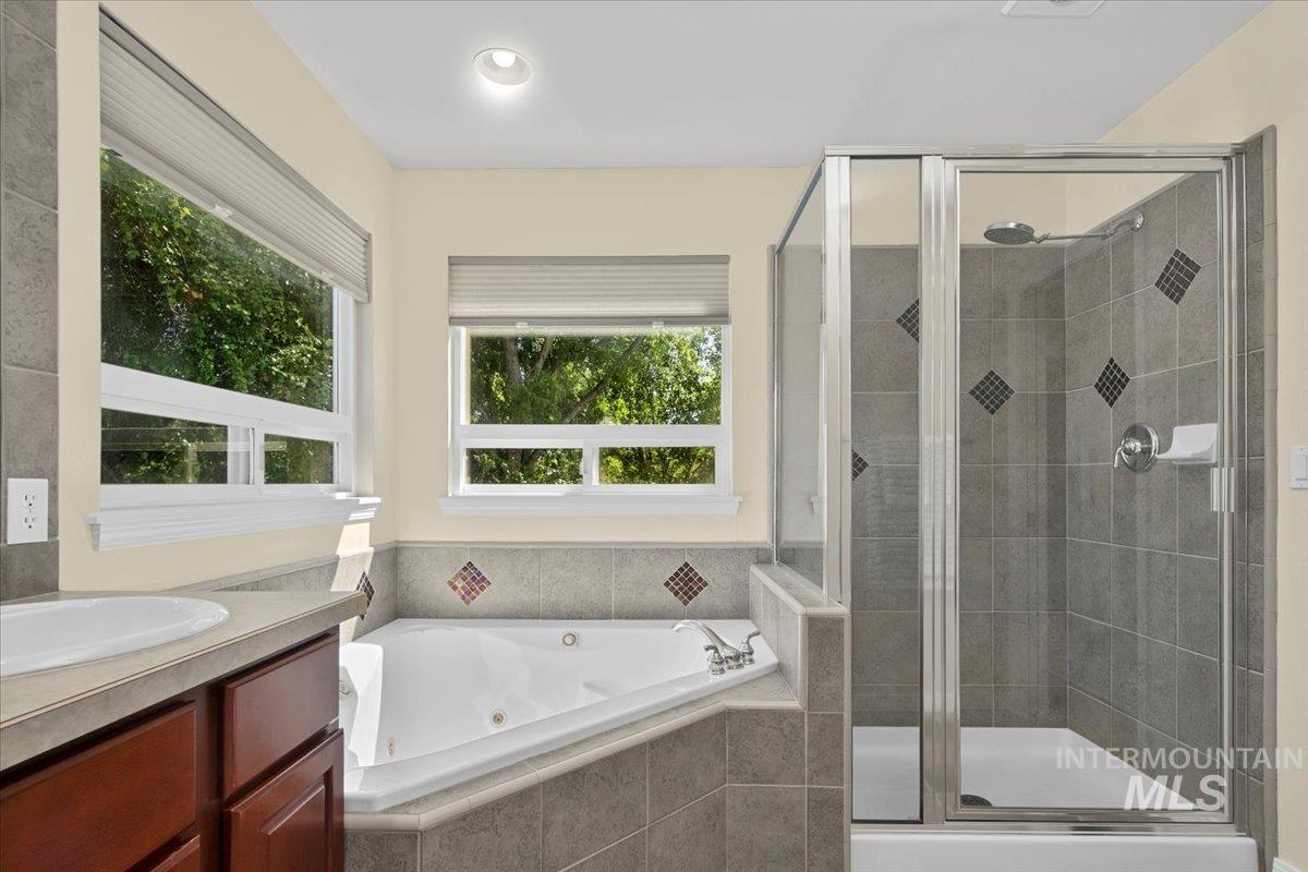 Full bath with a shower stall, a tub with jets, and vanity