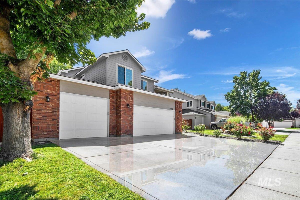 Traditional-style house with brick siding, concrete driveway, an attached garage, and a residential view