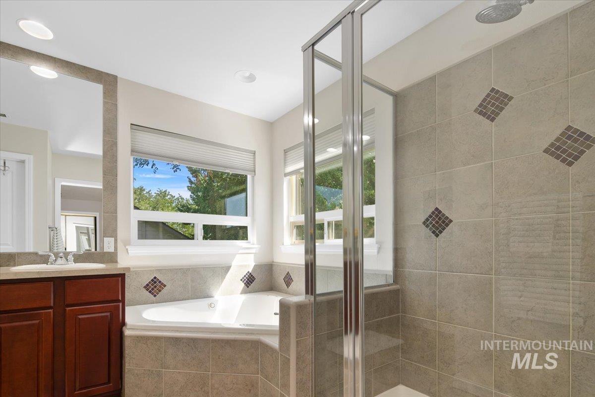 Full bath with a stall shower, vanity, and a bath