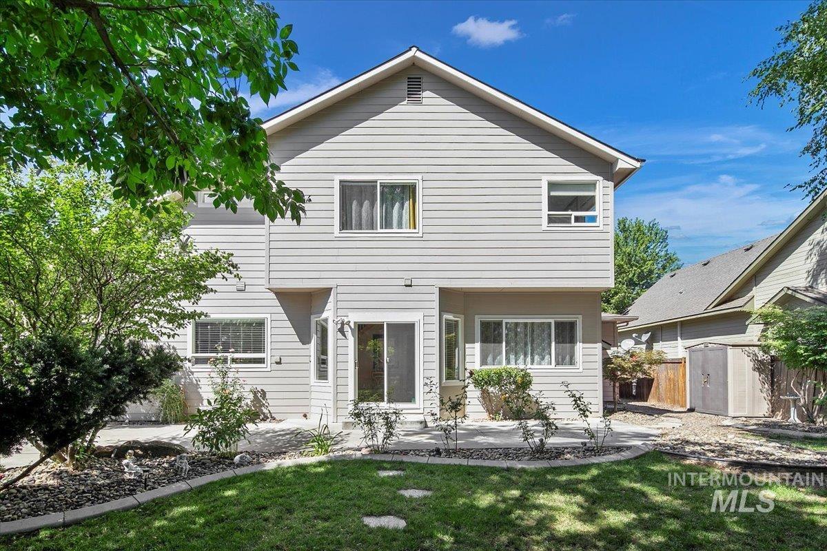 Back of property with a patio, a storage unit, and a yard