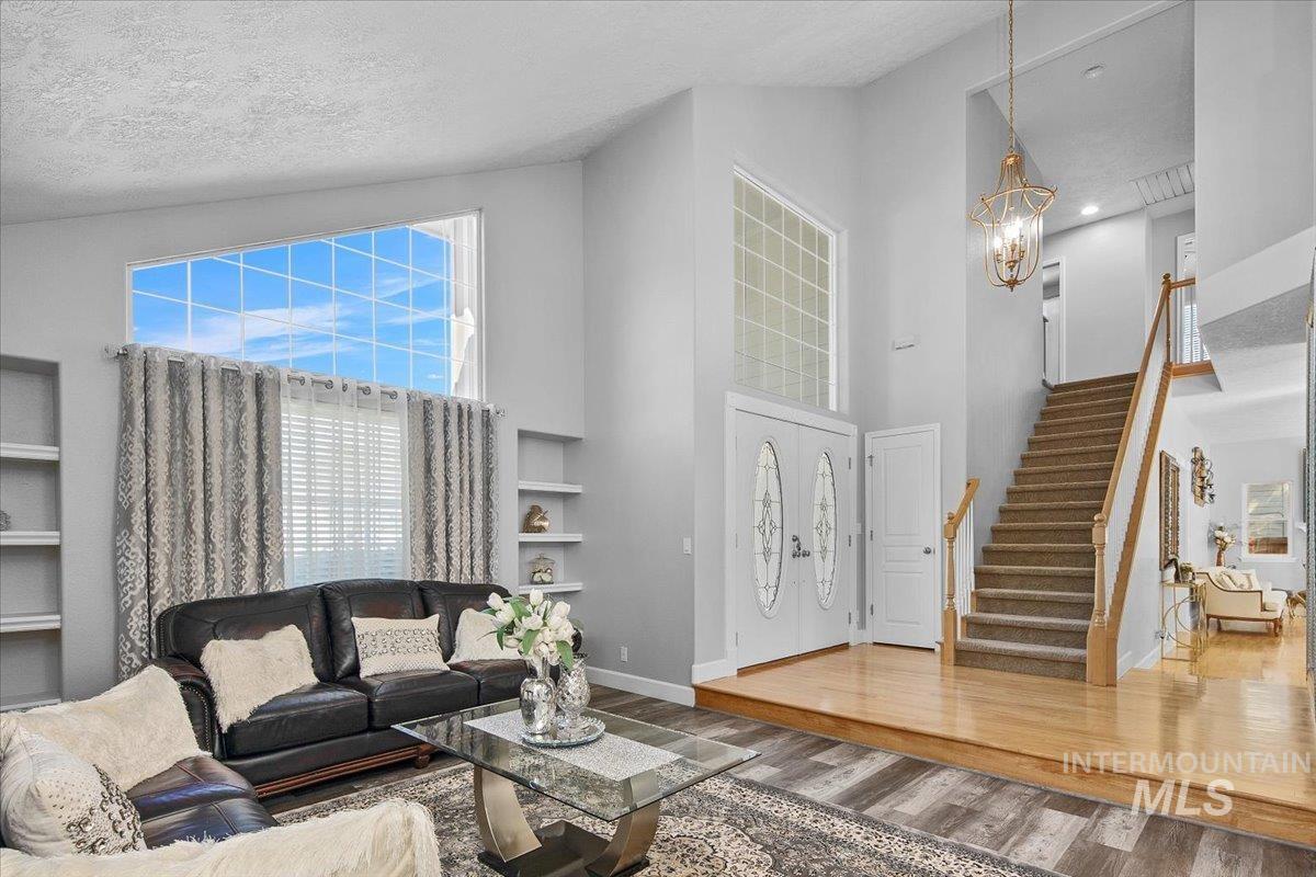 Living room with wood finished floors, plenty of natural light, a towering ceiling, a textured ceiling, and built in shelves