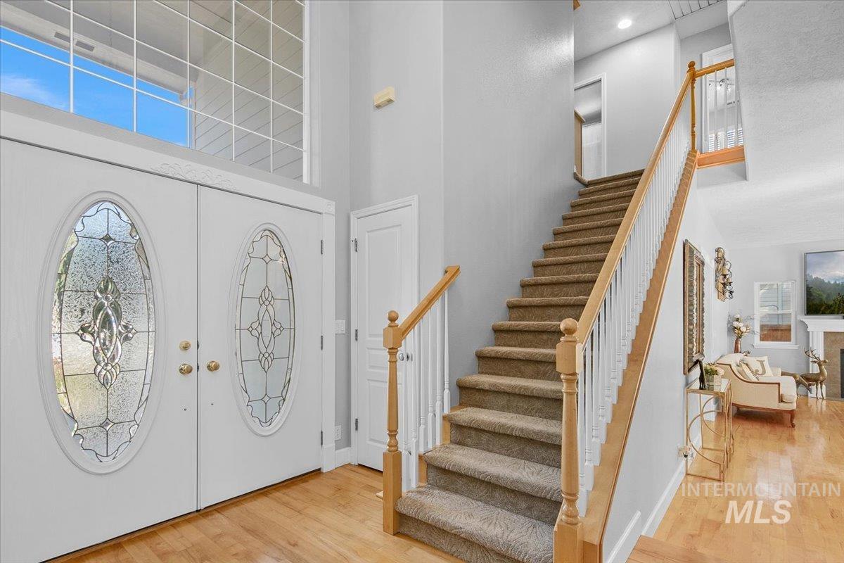Foyer entrance featuring a high ceiling, french doors, light wood-type flooring, and stairway
