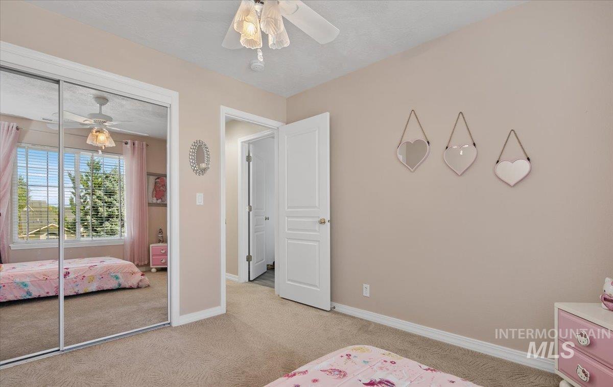 Bedroom featuring light carpet, a closet, a ceiling fan, and a textured ceiling
