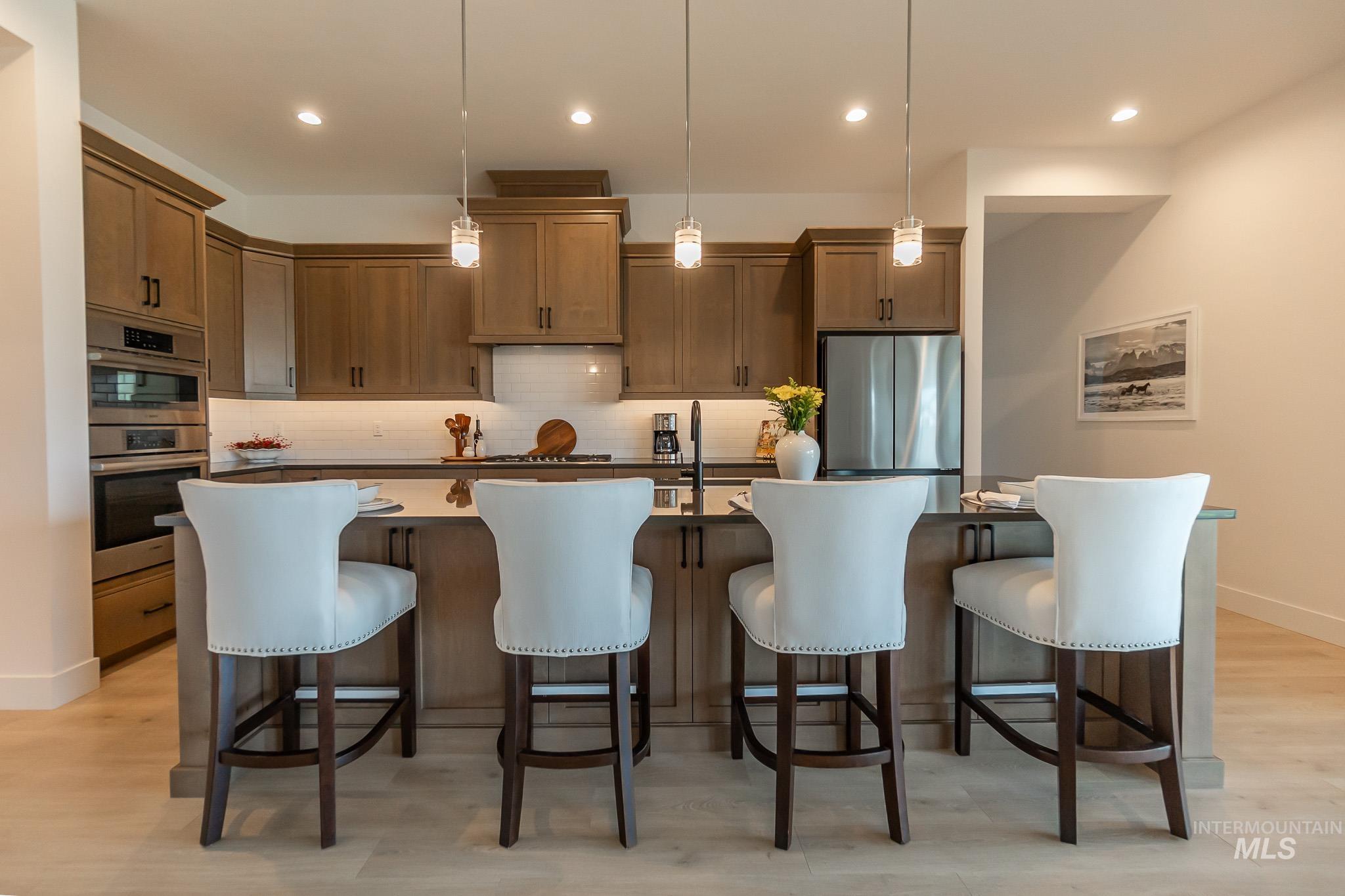 Kitchen featuring appliances with stainless steel finishes, backsplash, a large island with sink, pendant lighting, and recessed lighting