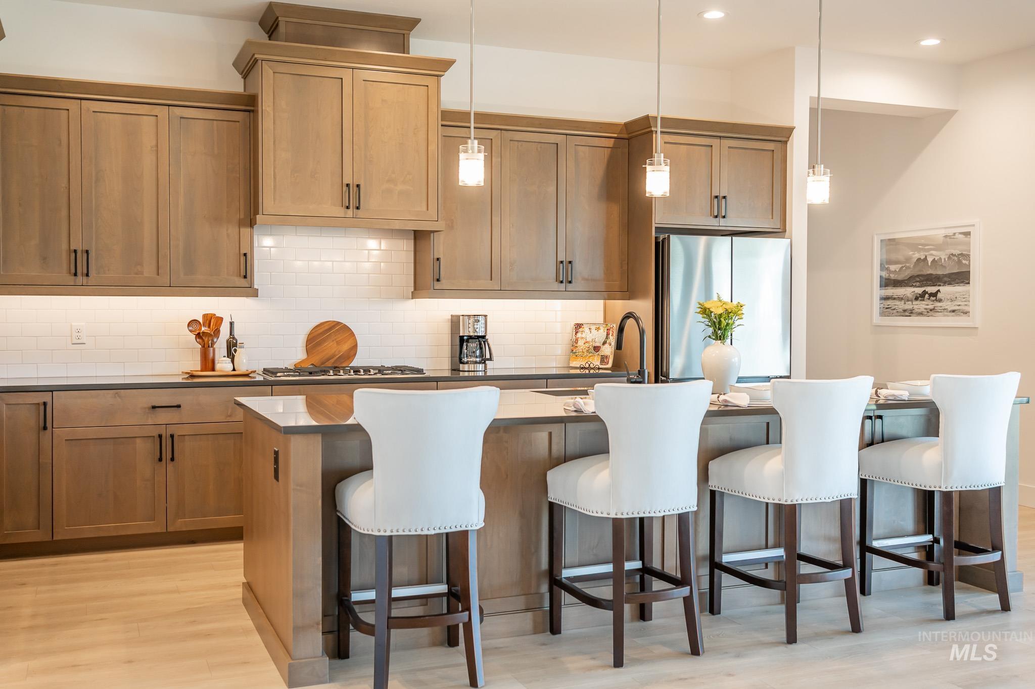 Kitchen with appliances with stainless steel finishes, light wood finished floors, decorative backsplash, a kitchen bar, and recessed lighting